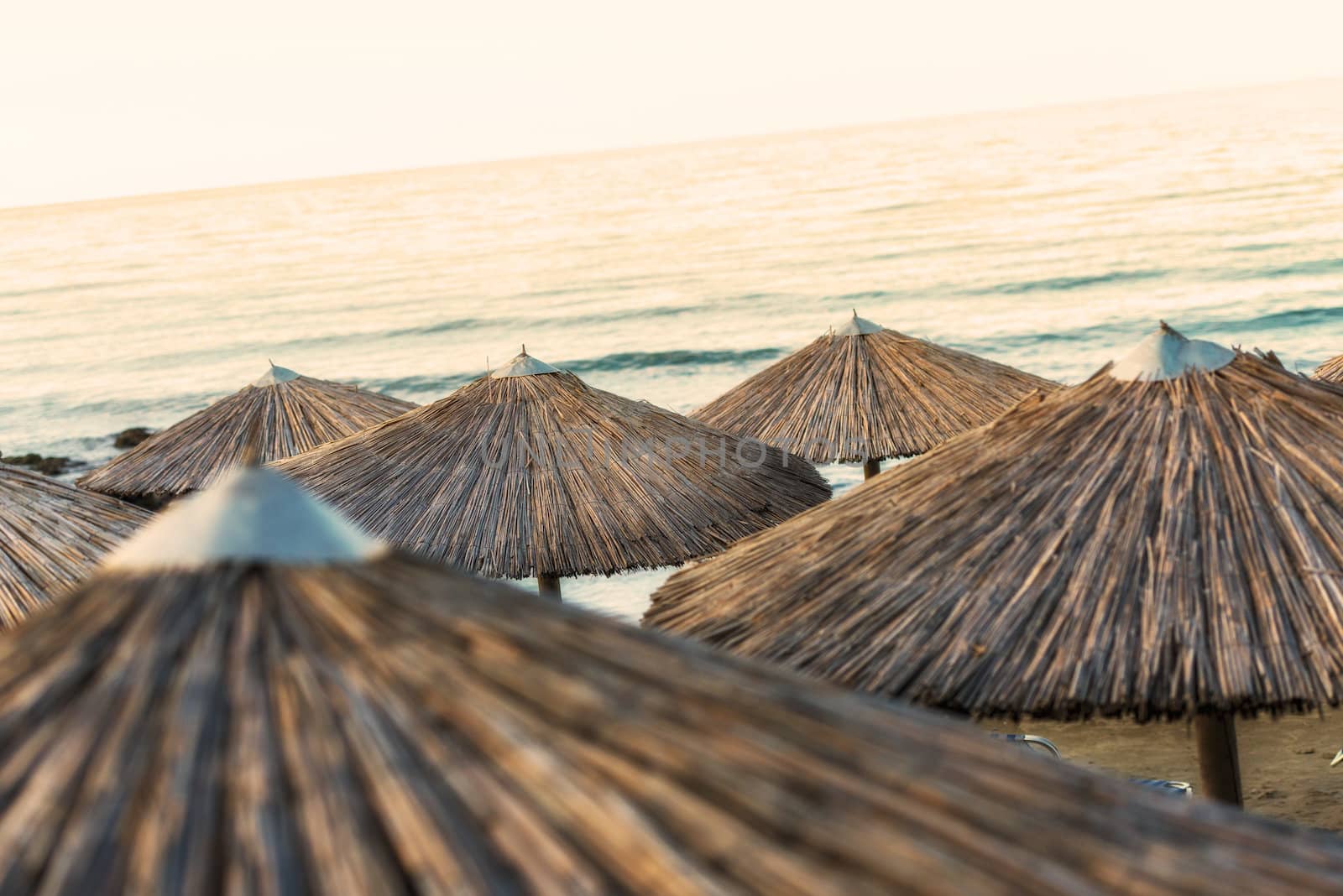 Beautiful Sandy Beach with Straw Umbrellas at Sunrise in Georgioupolis, Island of Crete, Greece