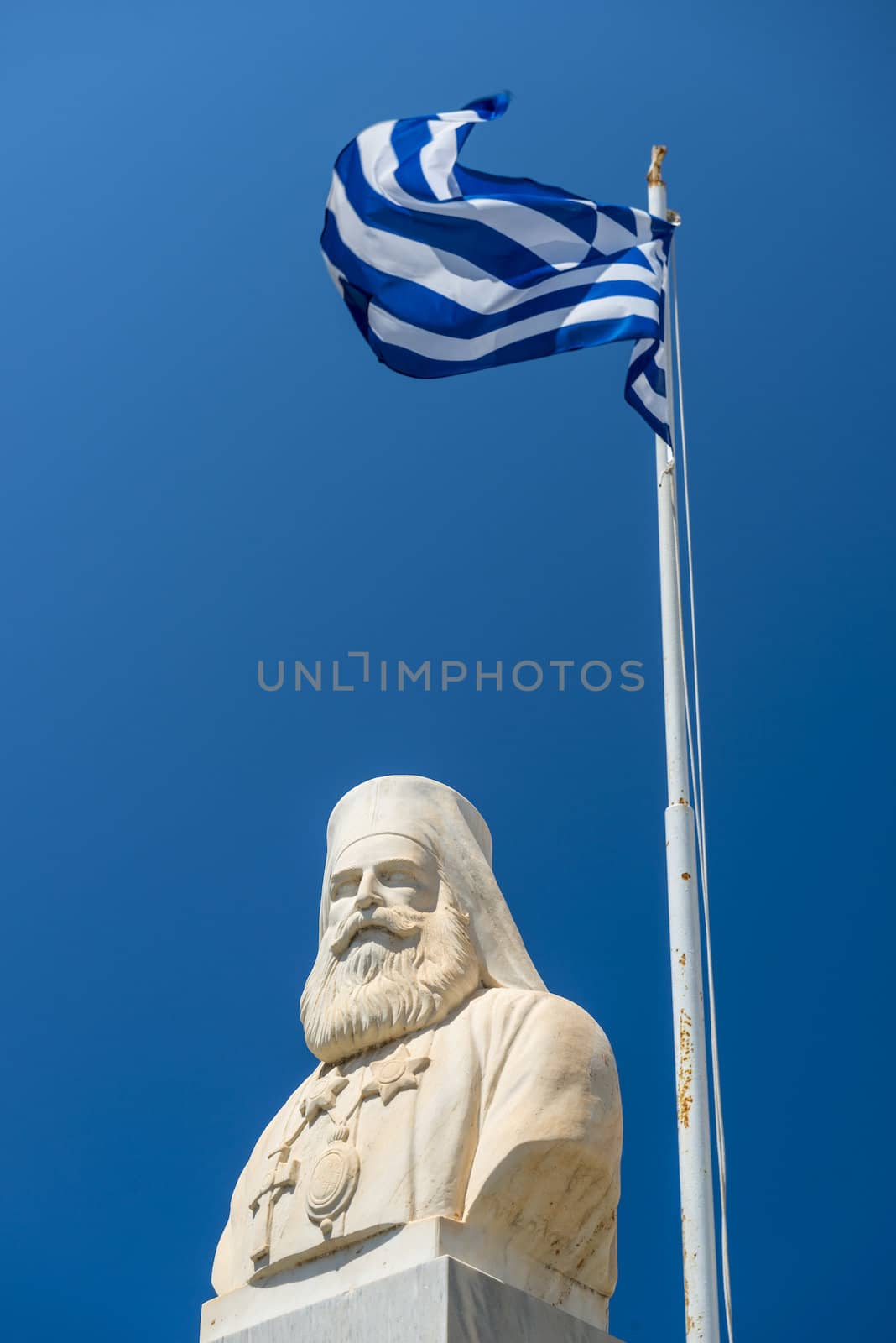 Statue Of The Famous Greek Writer, Nikos Kazantzakis With Waving Greek Flag