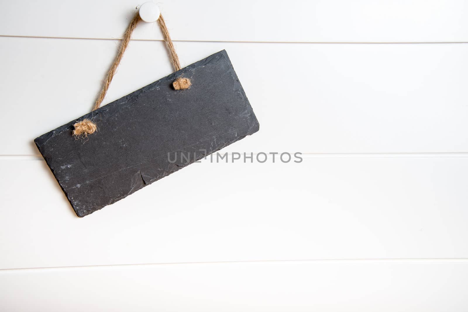 Black stone slate blank sign hanging on white wooden door