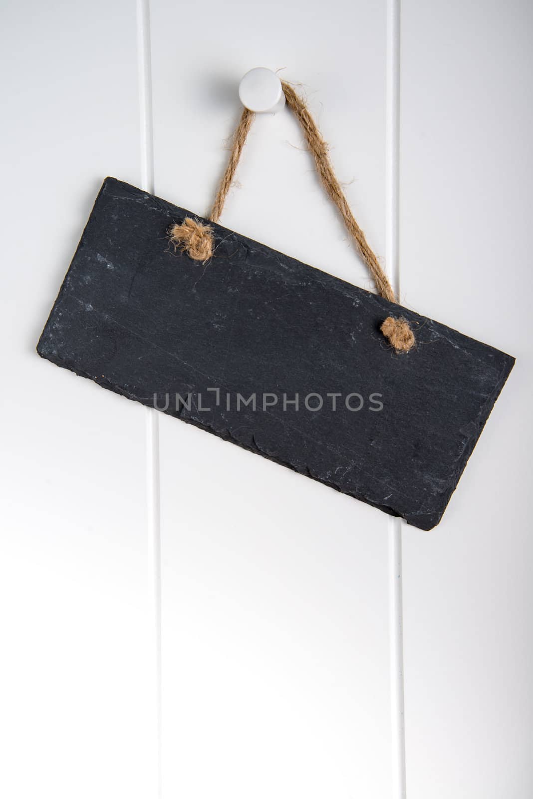 Black stone slate blank sign hanging on white wooden door