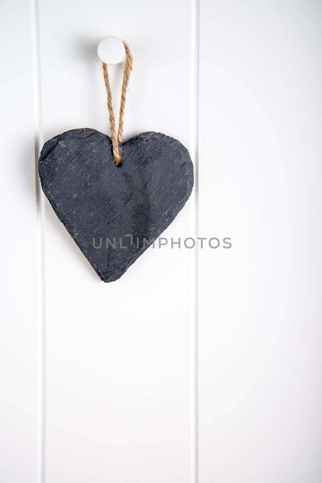 Black stone slate herath shape blank sign hanging on white wooden door
