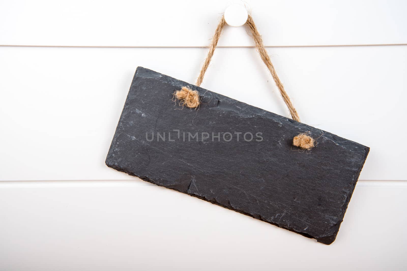 Black stone slate blank sign hanging on white wooden door