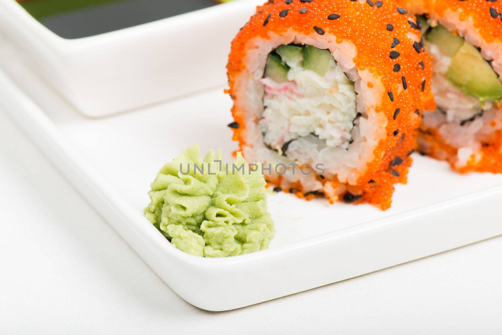 Macro shot of wasabi with sushi rolls on background