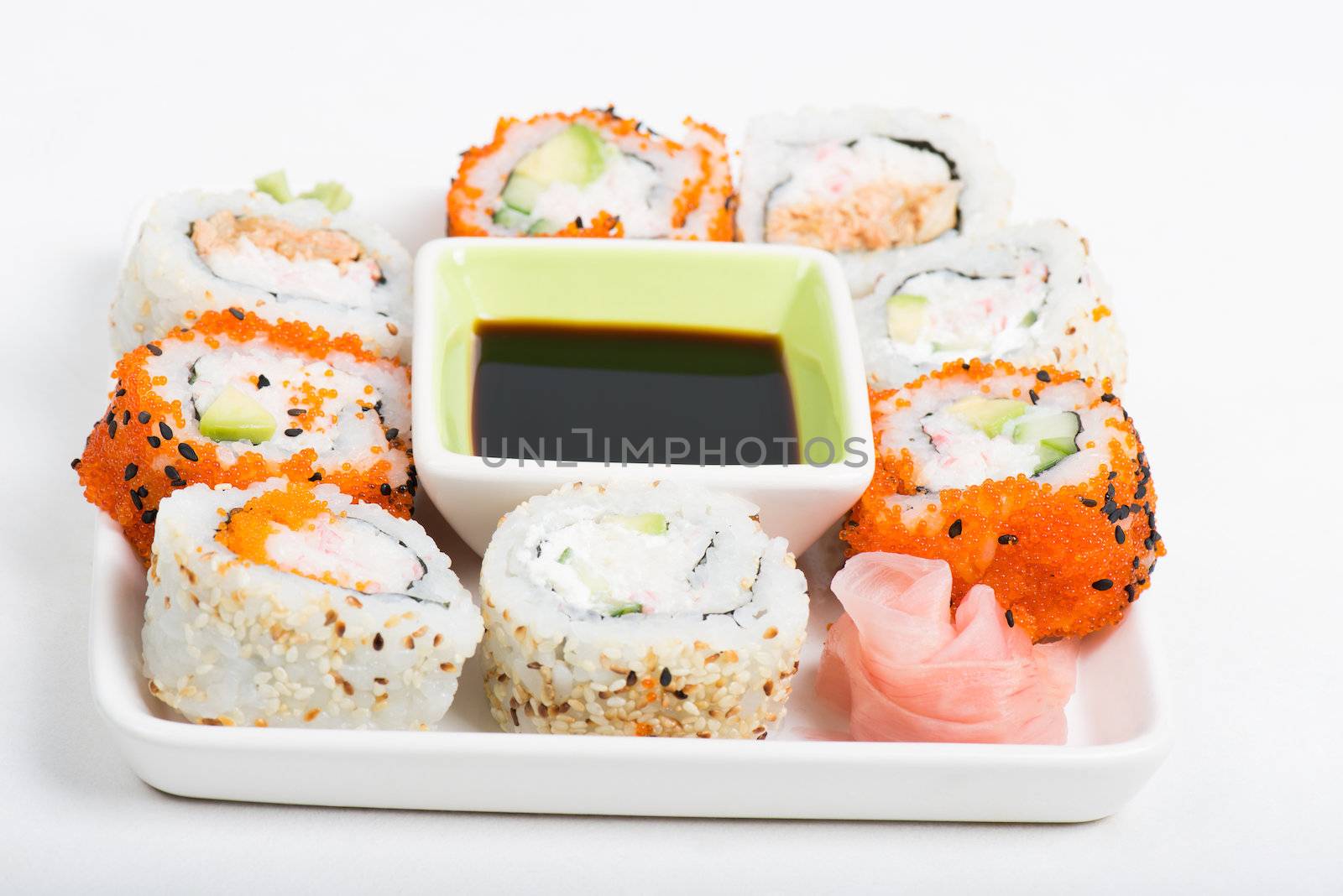 Different sorts of sushi rolls with soy sauce on the plate