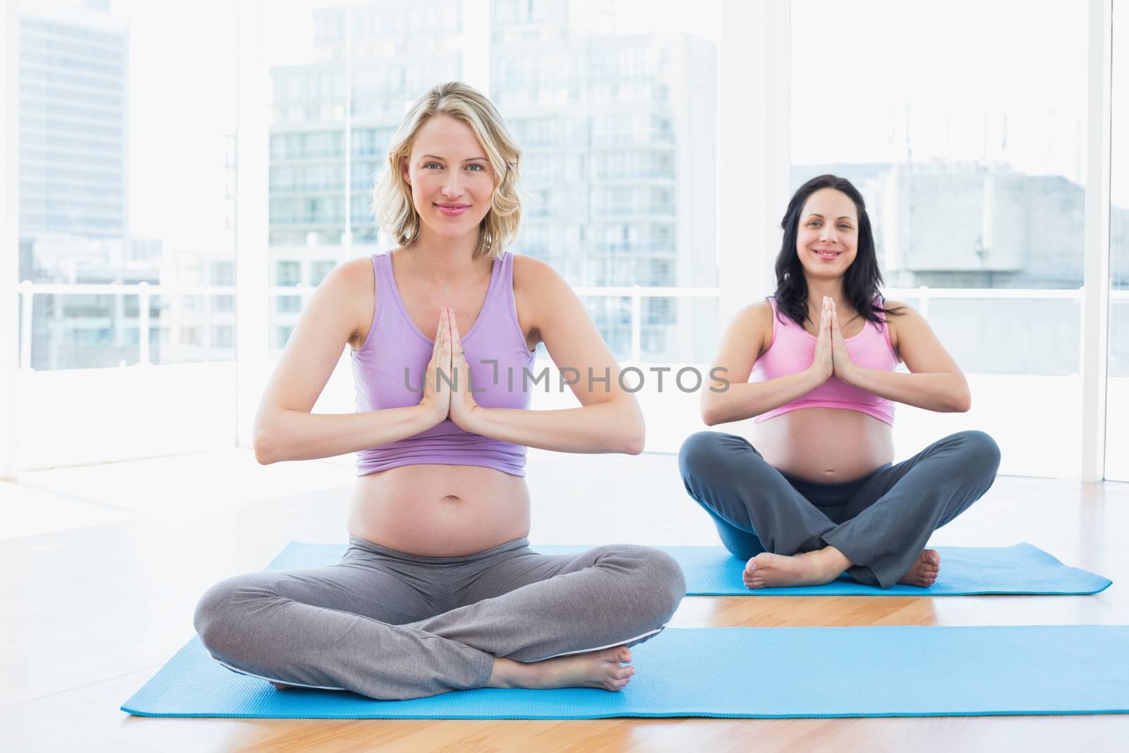 Happy pregnant women in yoga class in lotus pose by Wavebreakmedia