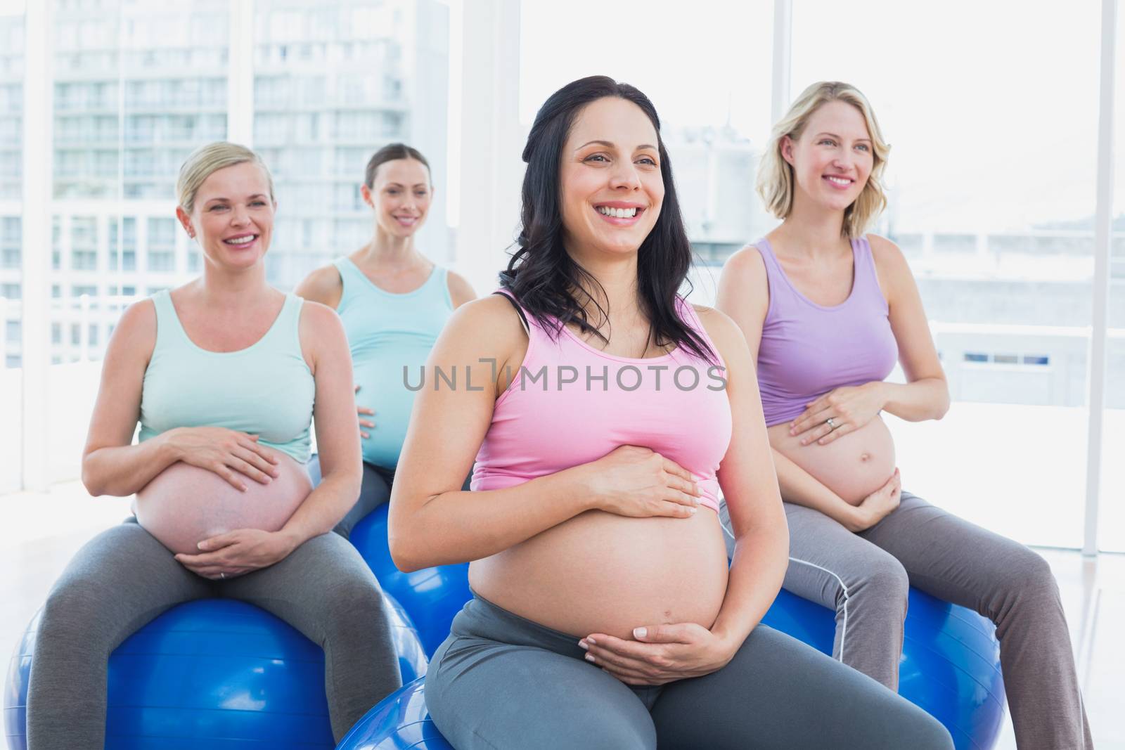 Happy pregnant women sitting on exercise balls  by Wavebreakmedia