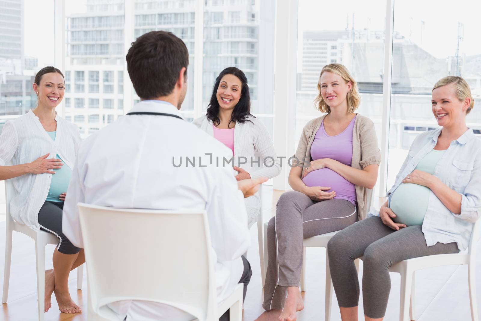 Happy pregnant women listening to doctor at antenatal class at the hospital