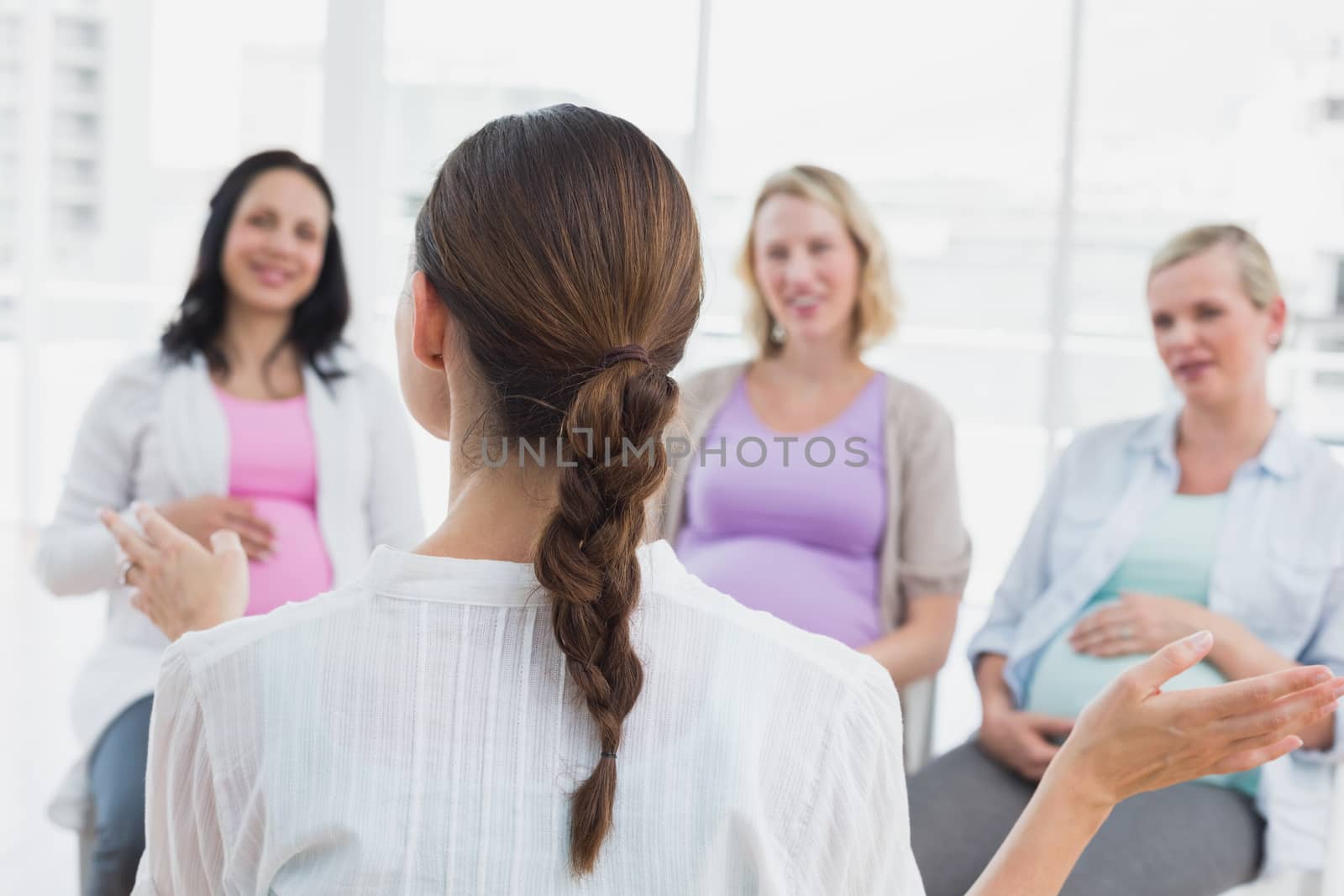 Happy pregnant women listening to gesturing doctor at antenatal class by Wavebreakmedia