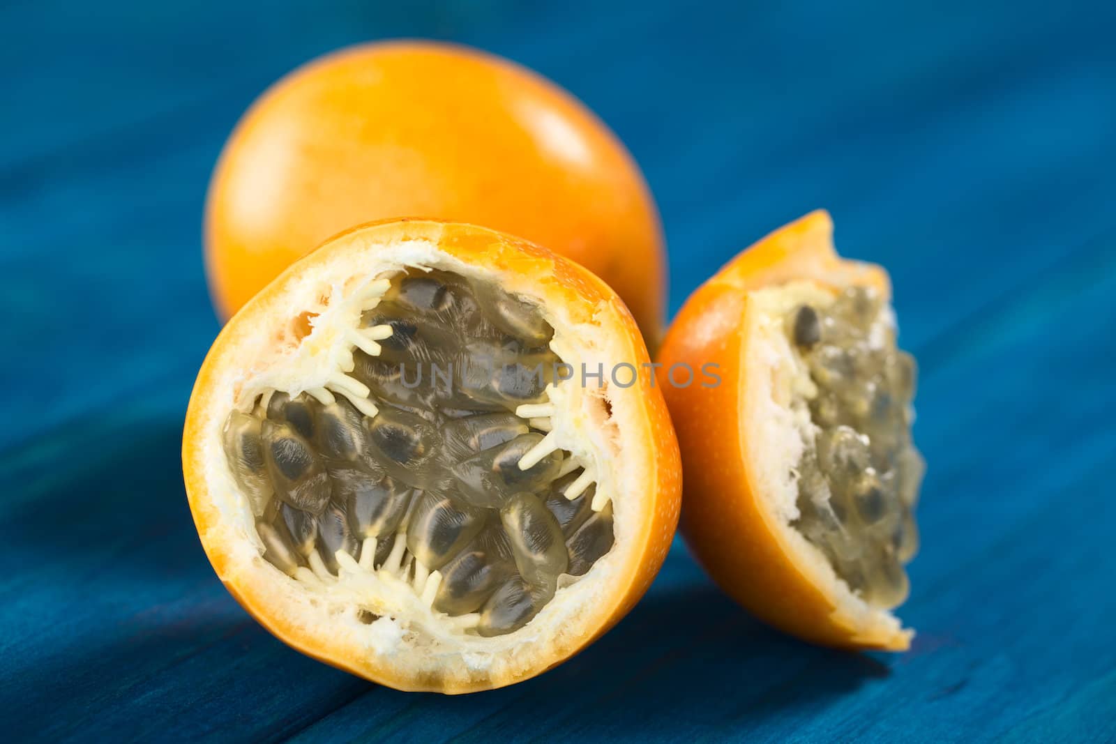 Sweet granadilla or grenadia (lat. Passiflora ligularis) fruit cut in half,  of which the seeds and the surrounding juicy pulp is eaten or is used to prepare juice (Selective Focus, Focus on the front of the seeds)