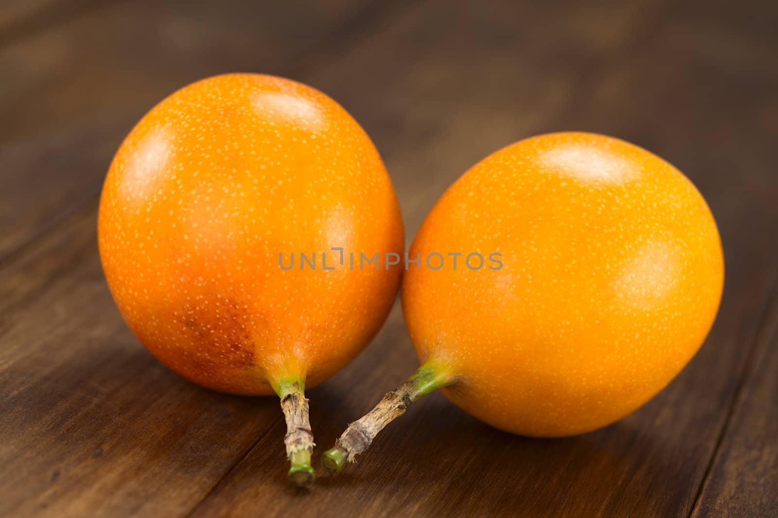 Two sweet granadilla or grenadia (lat. Passiflora ligularis) fruits,  of which the seeds and the surrounding juicy pulp is eaten or is used to prepare juice (Selective Focus, Focus on the front of the granadillas)