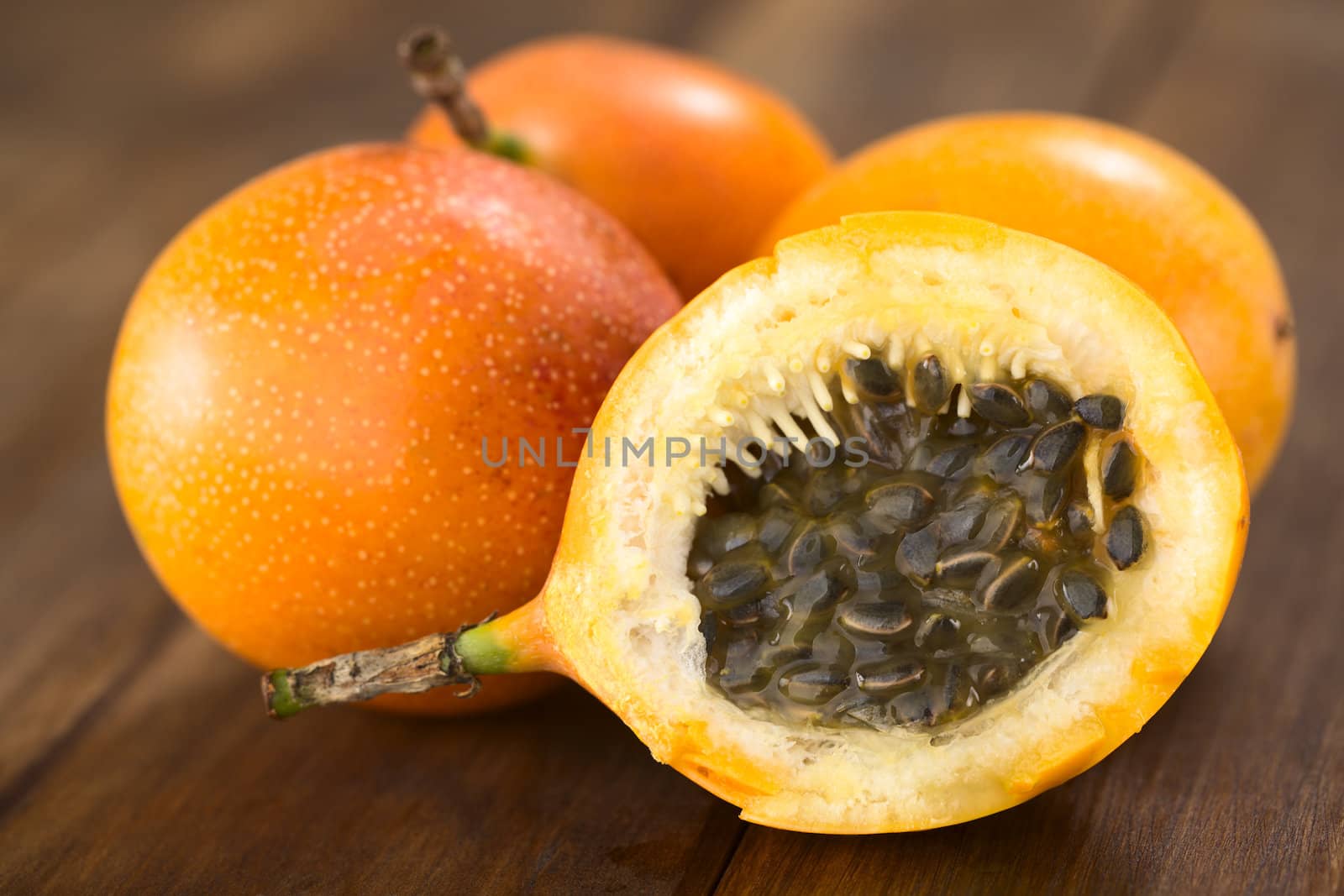 Sweet granadilla or grenadia (lat. Passiflora ligularis) fruit cut in half,  of which the seeds and the surrounding juicy pulp is eaten or is used to prepare juice  (Selective Focus, Focus on the front of the seeds)