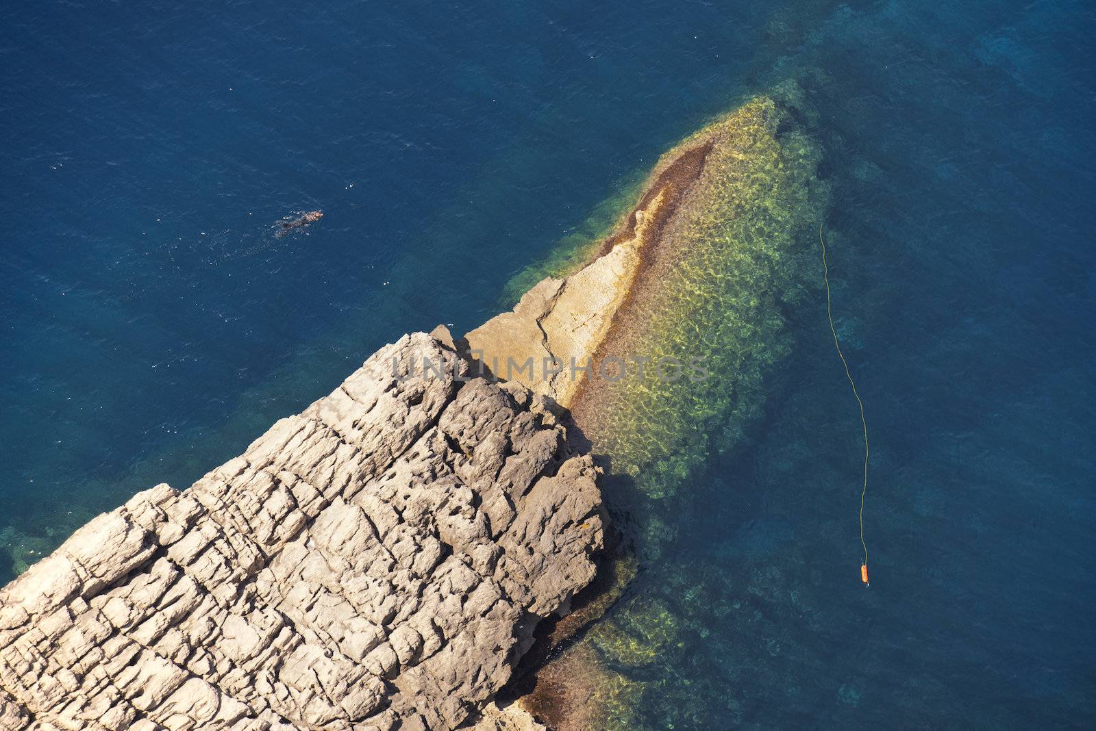 Lonely Diver in the Water by the Rocks of Cala Figuera in Mallorca, Spain ( Balearic Islands )