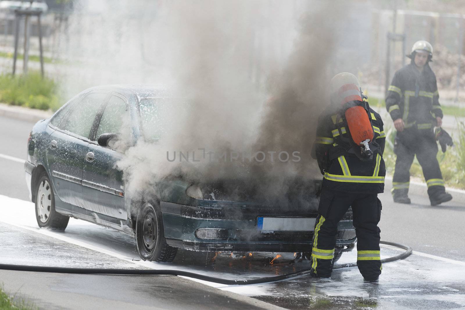 Burning motor vehicle been put out by firemen in protective clot by Rainman