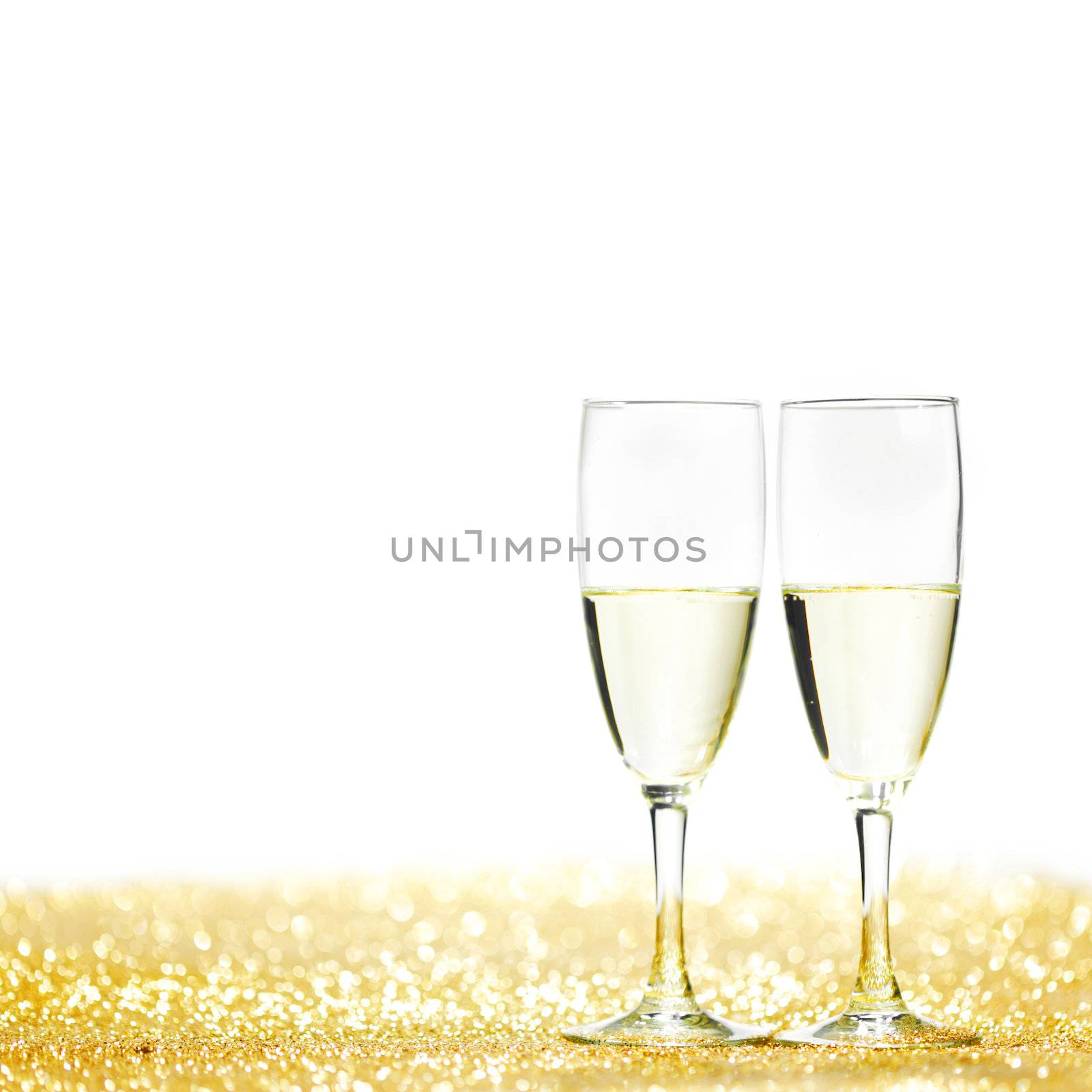 Pair of champagne flutes on shiny glitter background