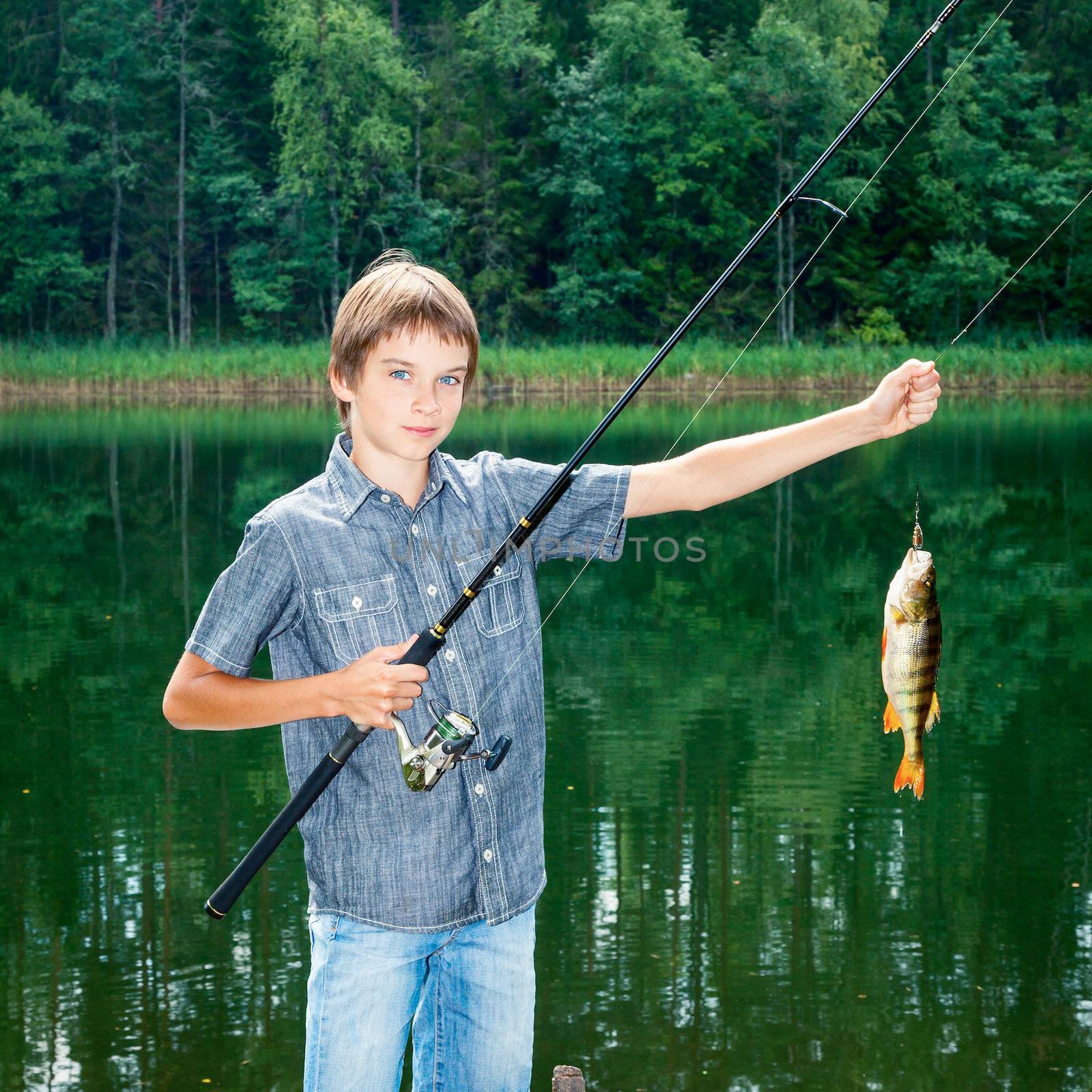 Cute boy showing fish he caught while fishing