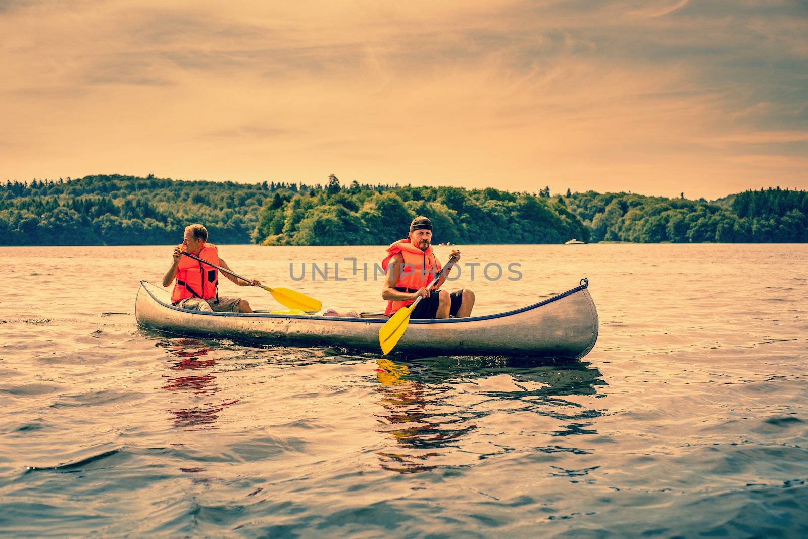 Men sailing a canoe wearing orange lifejackets