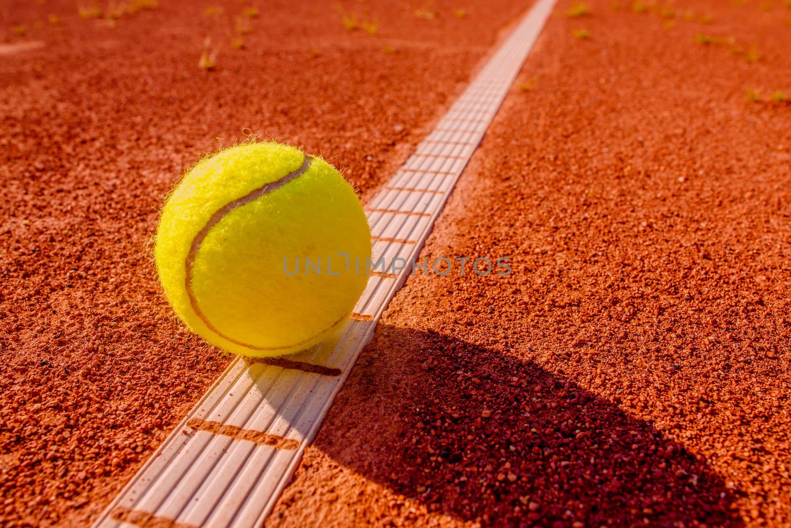 Yellow tennisball on the line at a clay court
