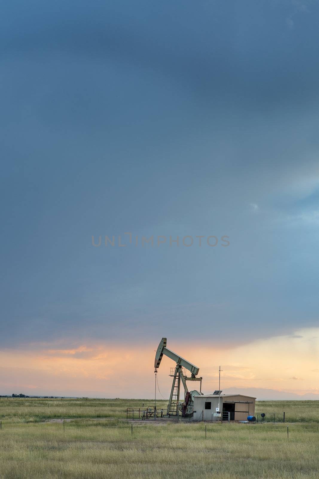 oil rug (pumpjack) against stormy sunset sky in Pawnee National Grassland near Grover, Colorado