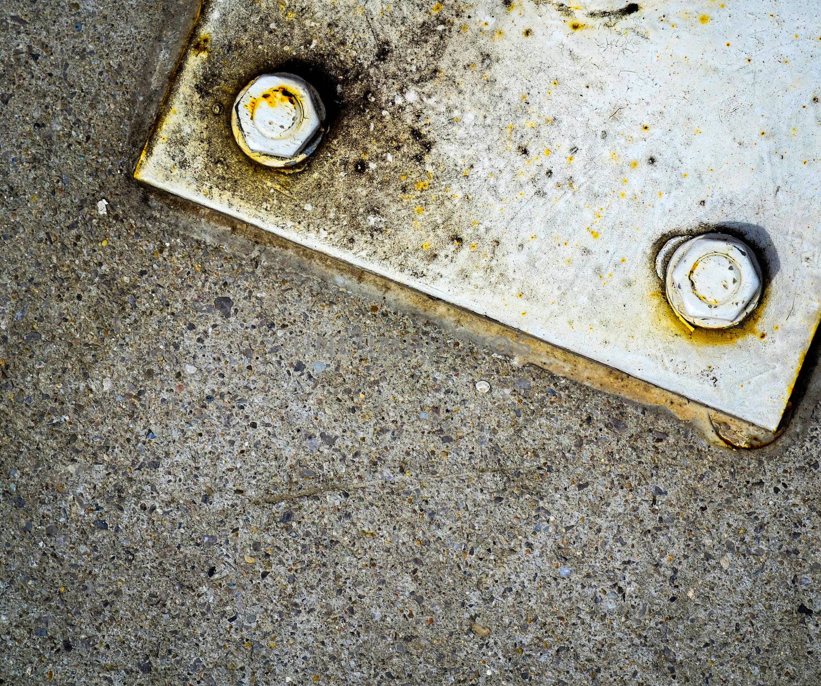 old white steel plate with two screws and nut on concrete