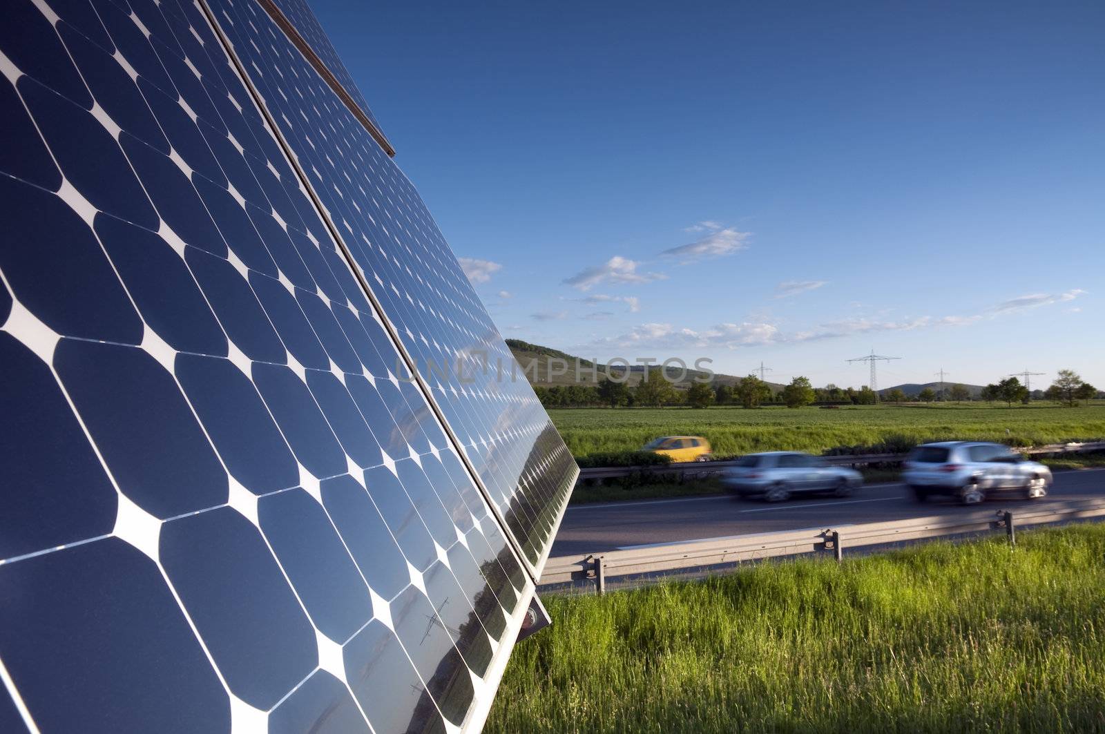 Solar Panel Against Blue Sky With Green Landscape And Highway