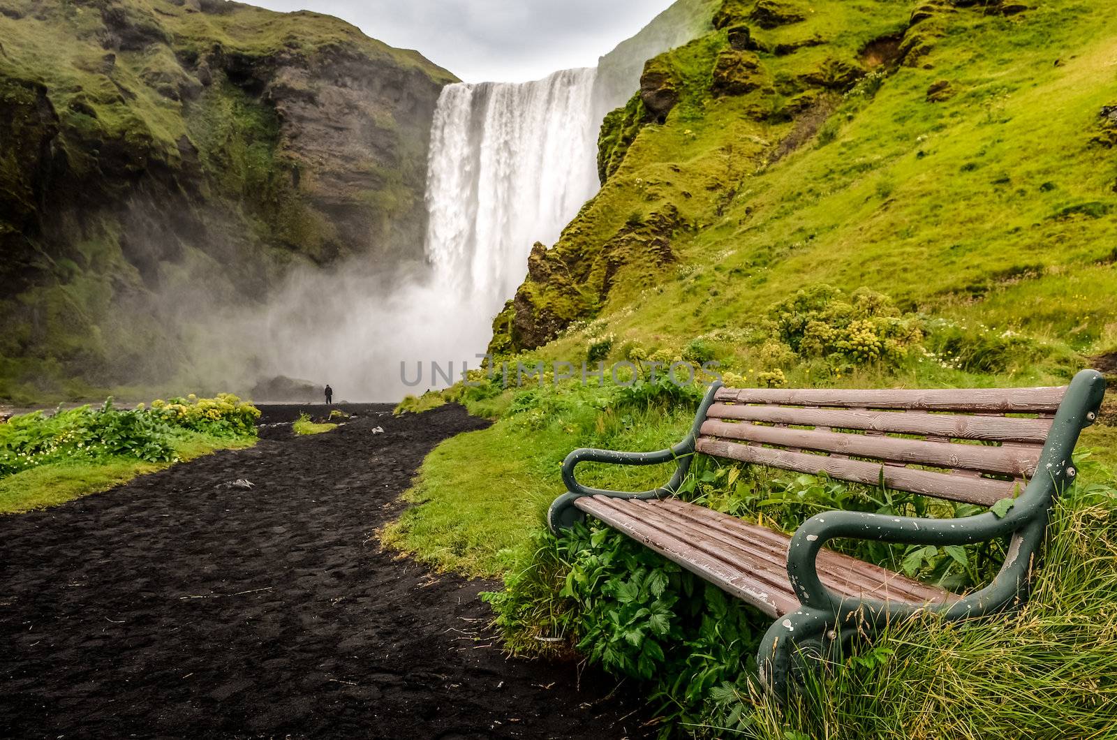 Landscape view of wild Skogafoss waterfall and bench, Iceland