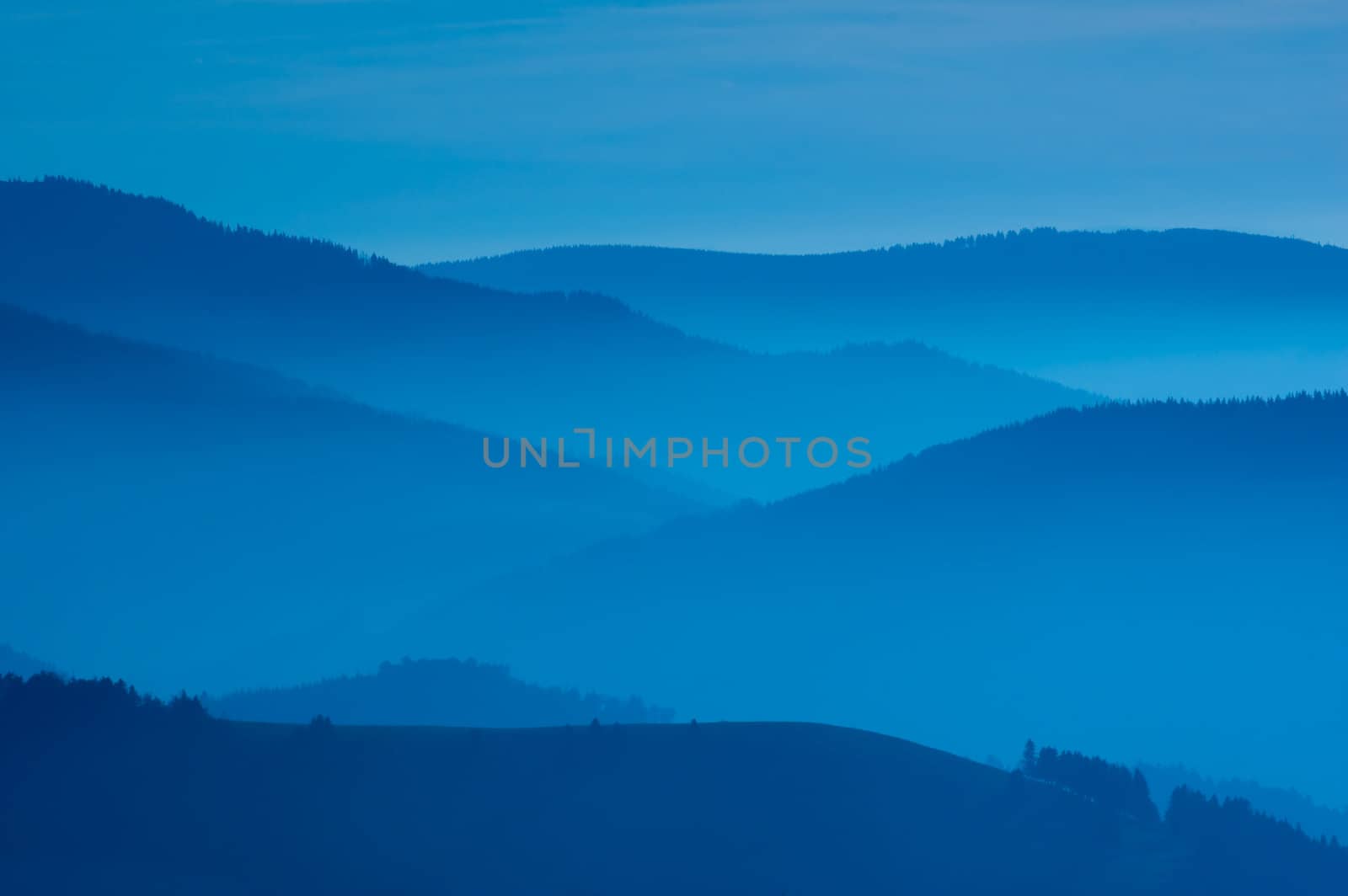 Misty morning of hilly area with ray of light.