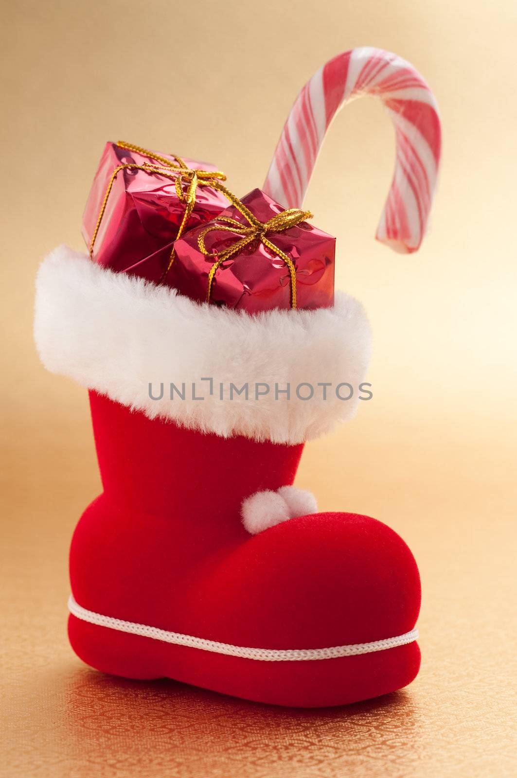 red christmas boot with gifts on gold background 