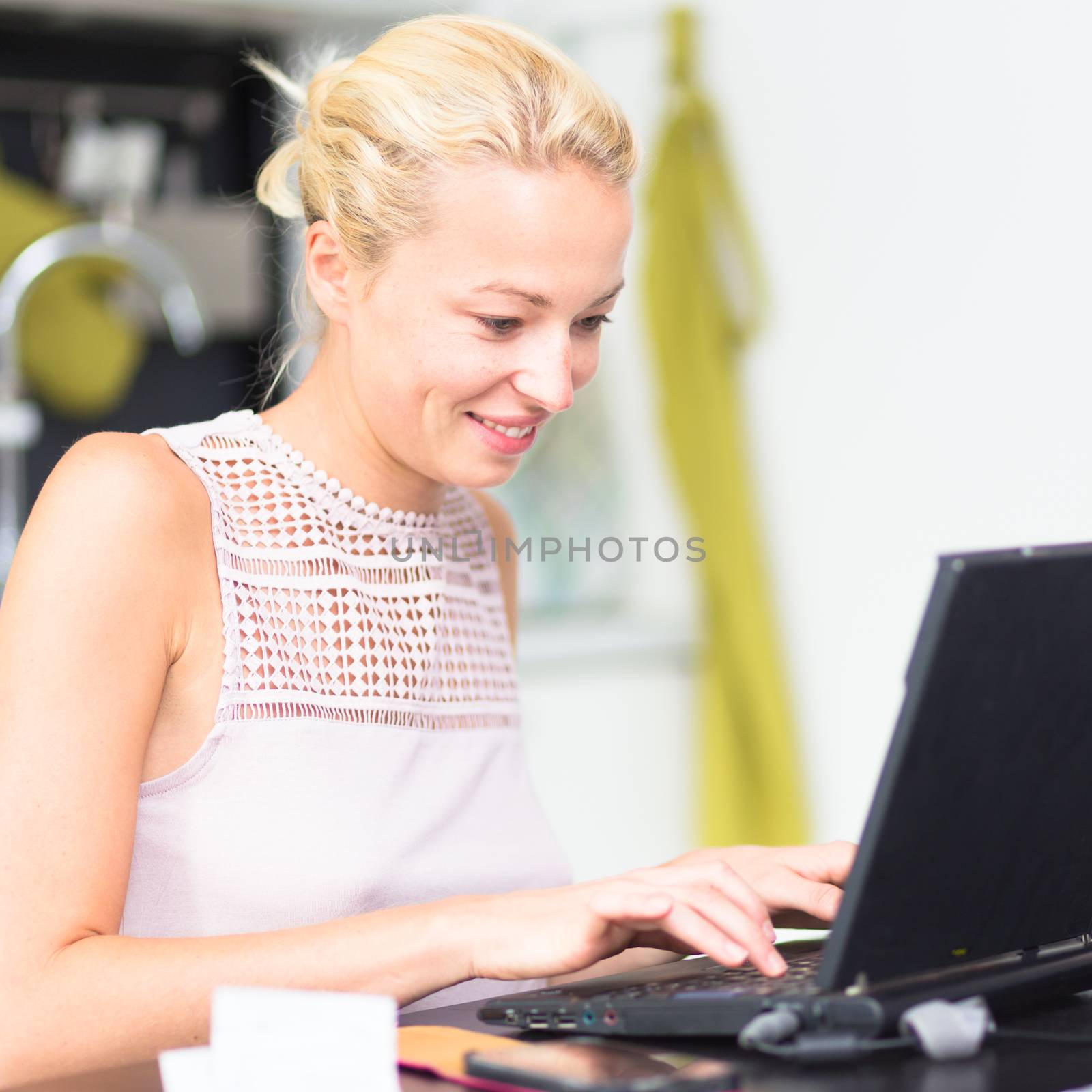 Business woman working remotly from her dining table. Home kitchen in the background.