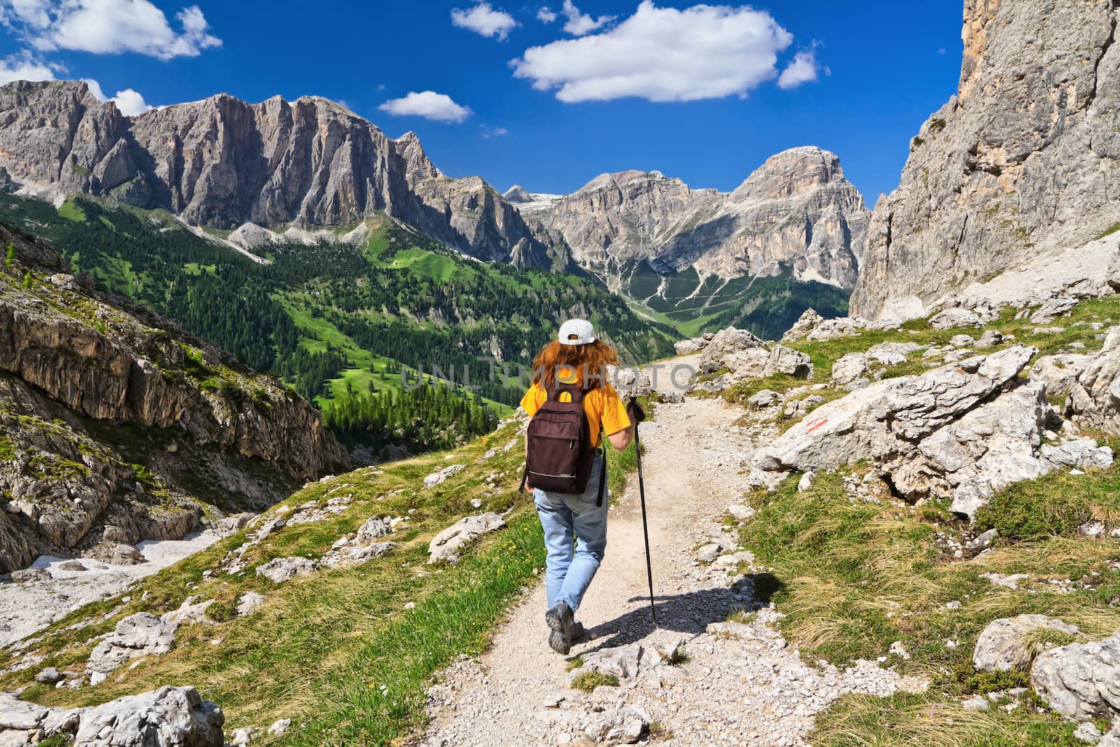 hiker on footpath  in Sella mountain, on background Colfosco and Badia Valley, south Tyrol, Italy