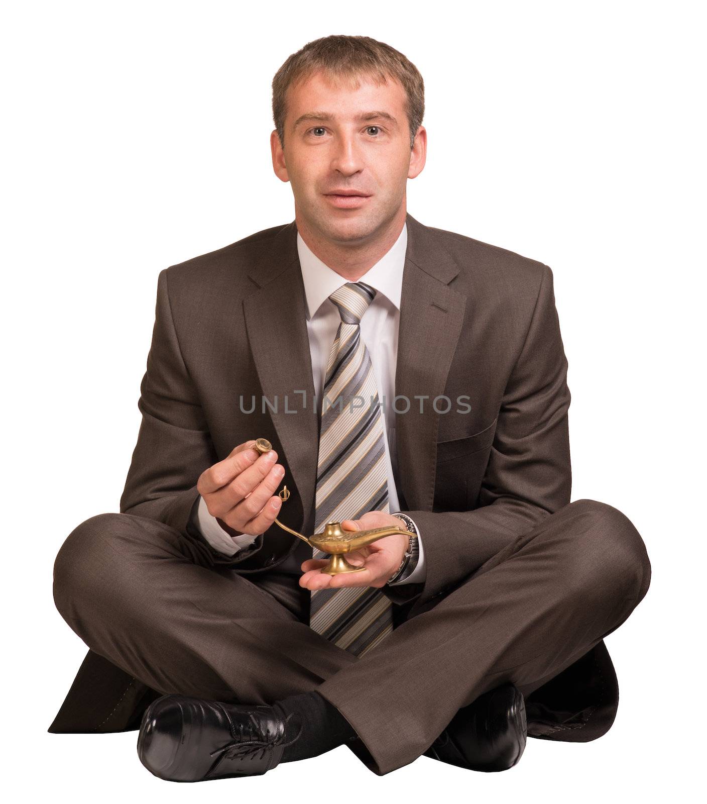 Businessman sitting in lotus position and hold gold lamp. Isolated on white background