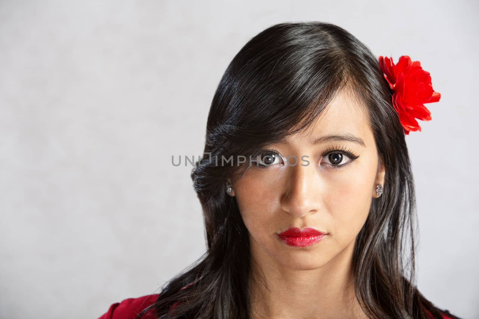 Calm beautiful Asian female with red flower