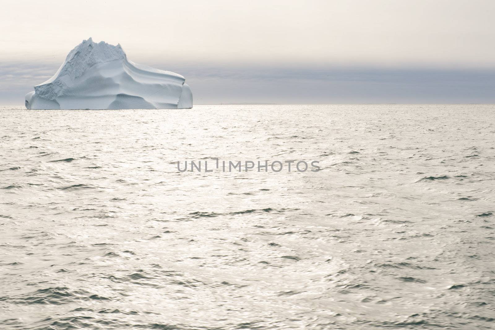 Sea and ocean landscape in greenland with dramatic sky, sun light, and iceberg