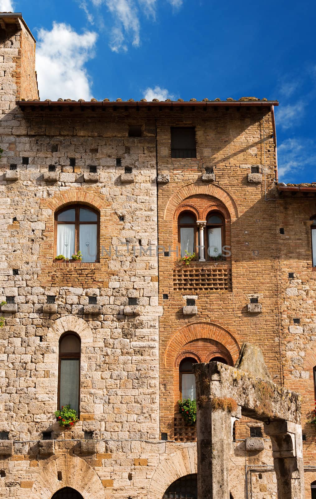 Old Buildings on the Cisterna square on blue sky, San Gimignano medieval town (UNESCO heritage), Siena, Tuscany, Italy