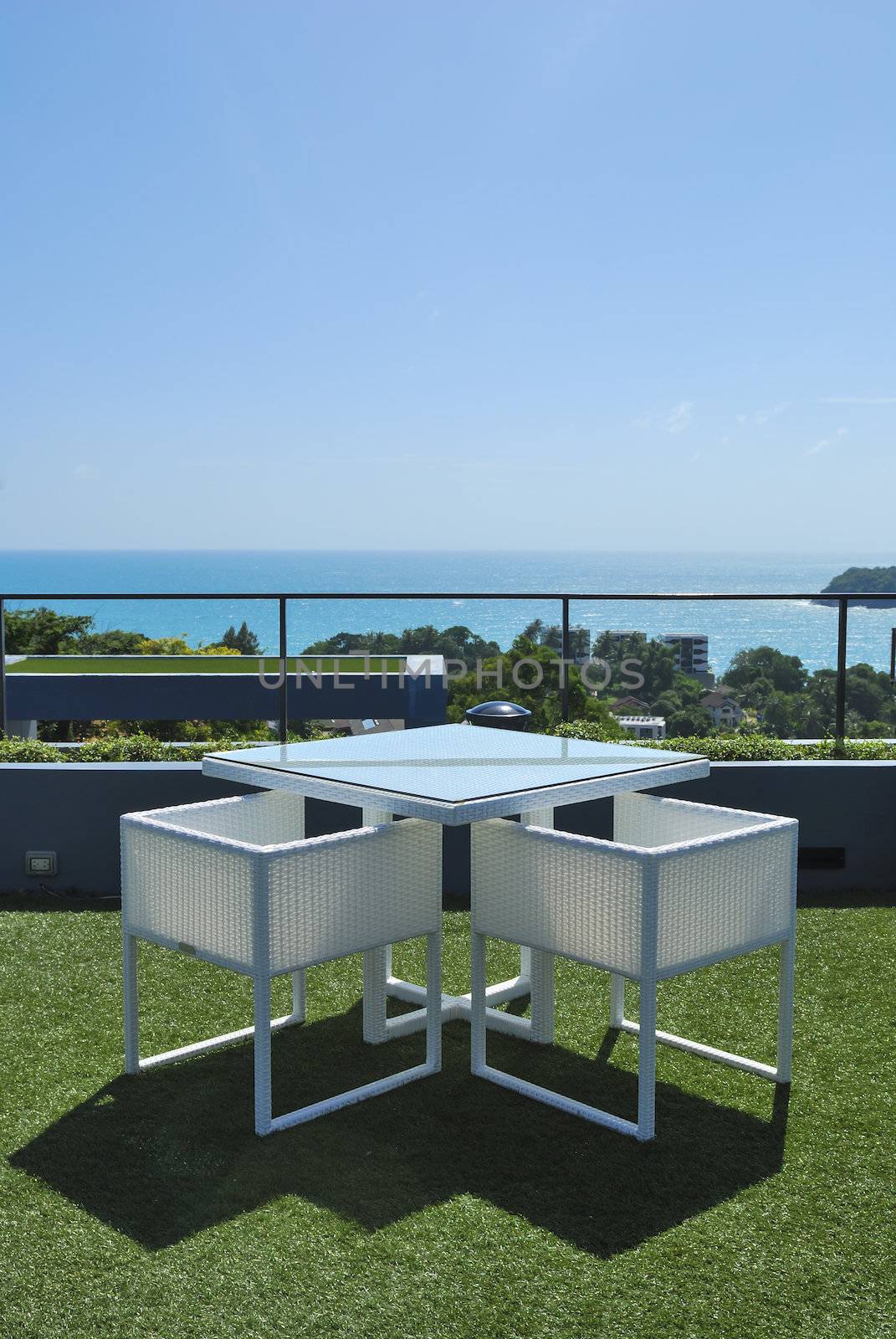 Terrace lounge with white rattan armchairs and seaview in a luxury resort .
