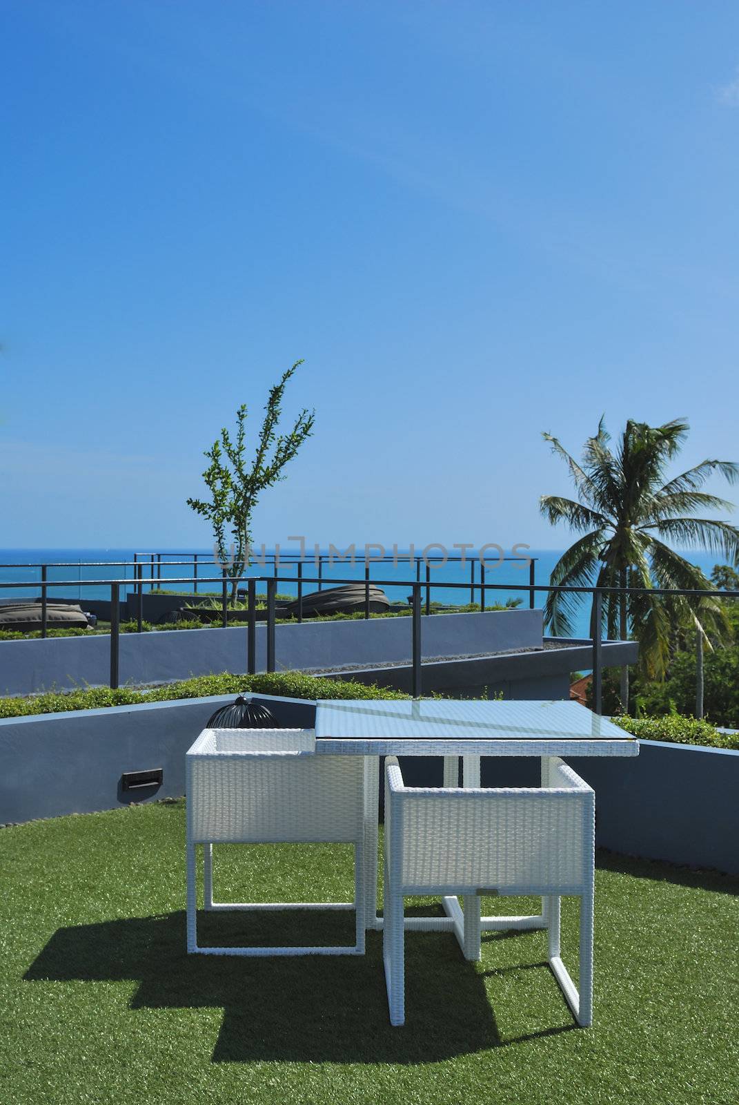 Terrace lounge with white rattan armchairs and seaview in a luxury resort .