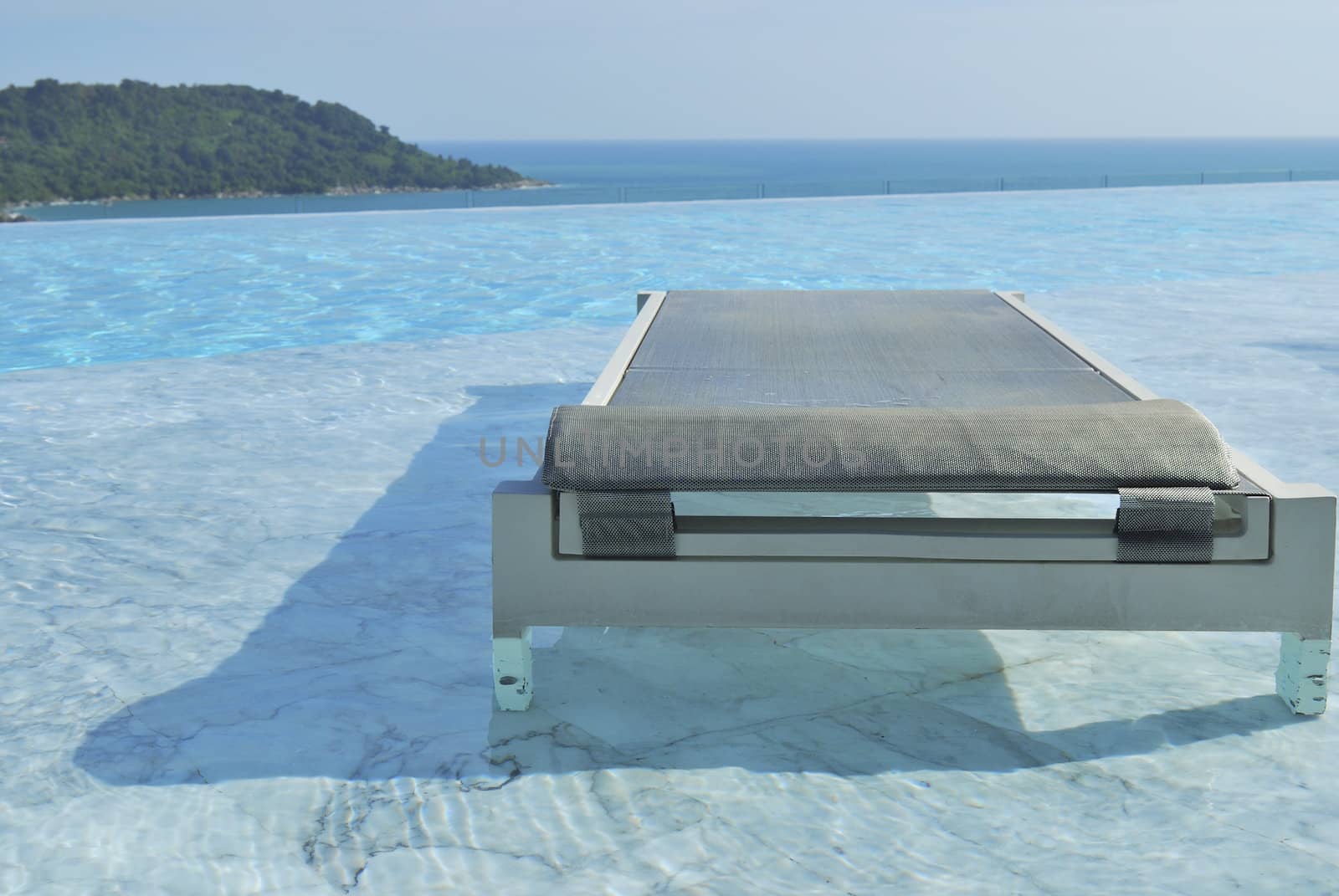 In summer vacation. Pool chairs on swimming pool seaview and blue sky.