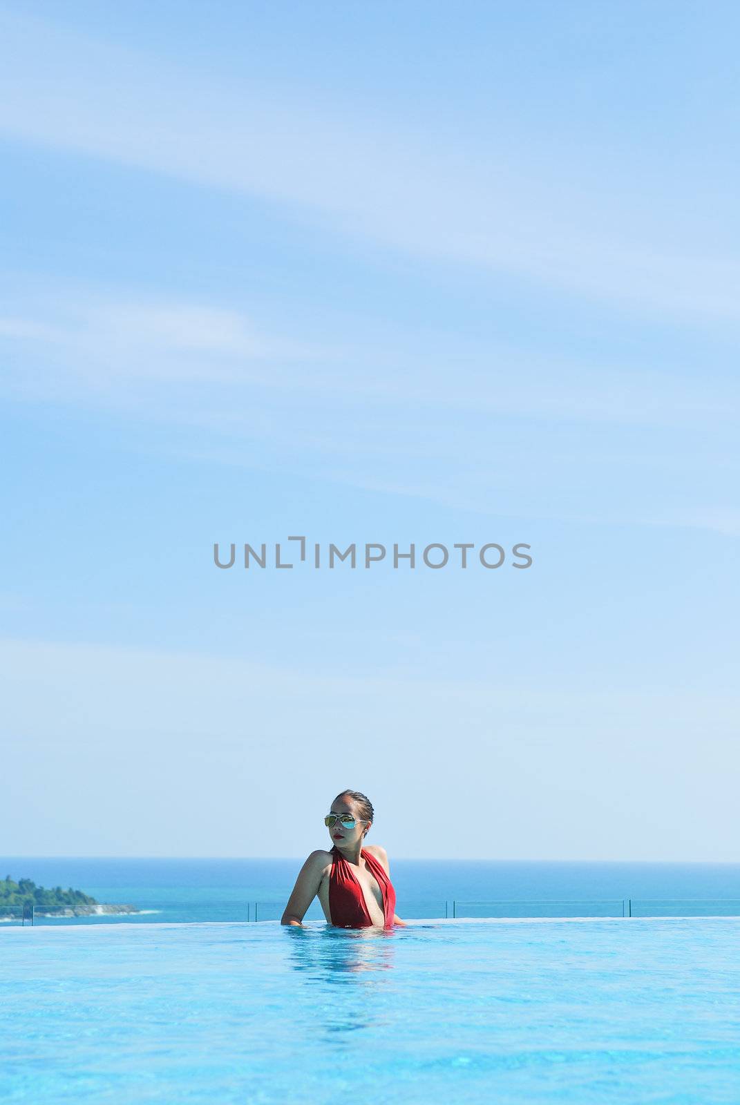 Summer vacations concept. Happy mother and daughter playing in blue water of swimming pool.