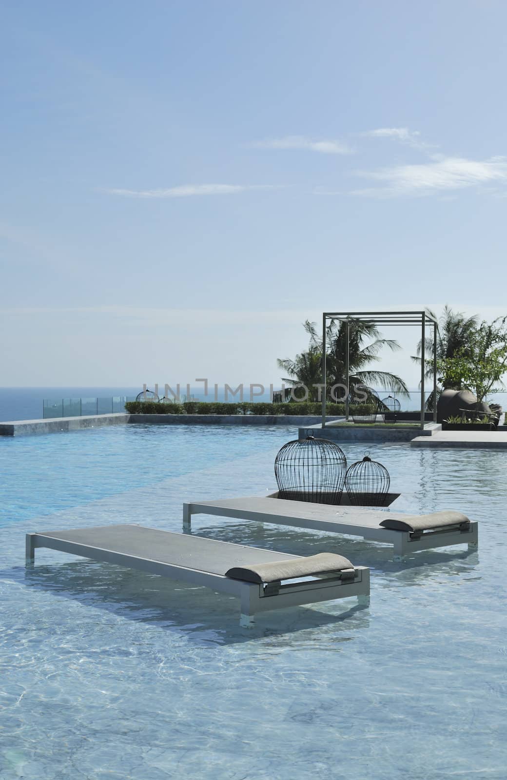 In summer vacation. Pool chairs on swimming pool seaview and blue sky.