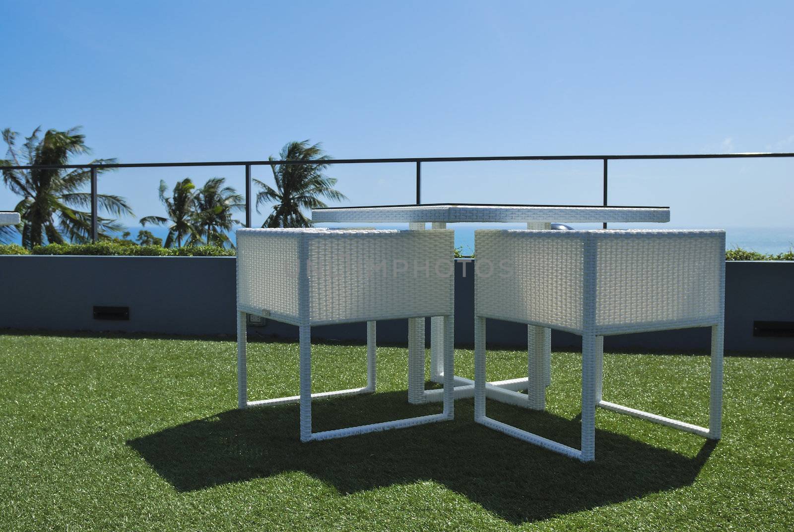 Terrace lounge with white rattan armchairs and seaview in a luxury resort .