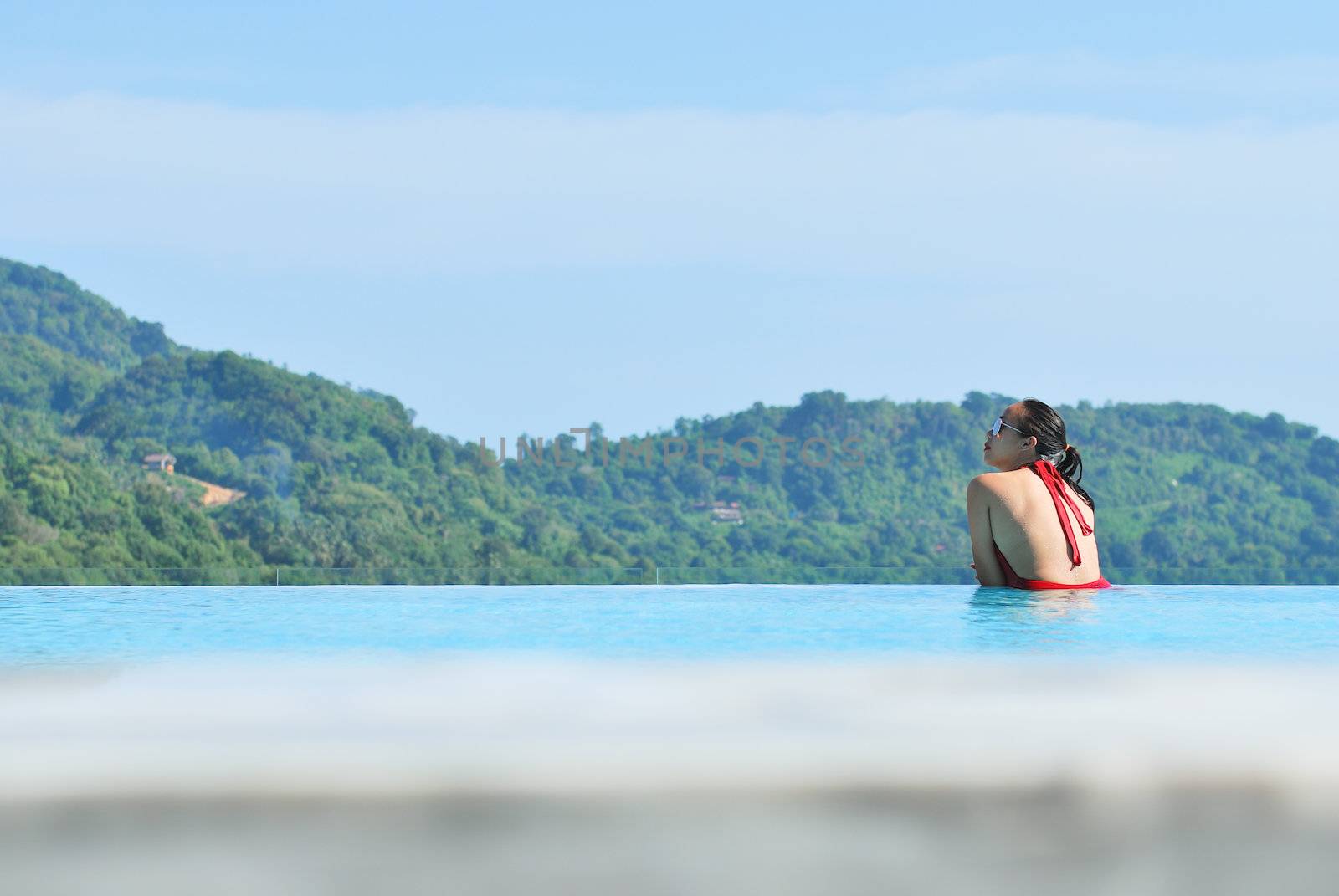 Summer vacations concept. Happy mother and daughter playing in blue water of swimming pool.