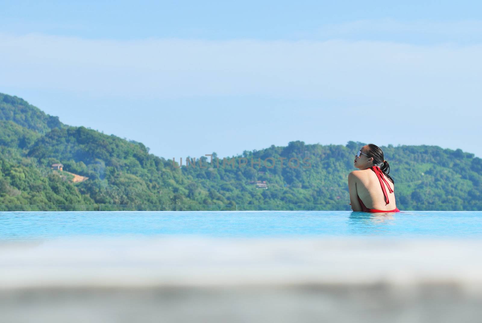 Summer vacations concept. Happy mother and daughter playing in blue water of swimming pool.