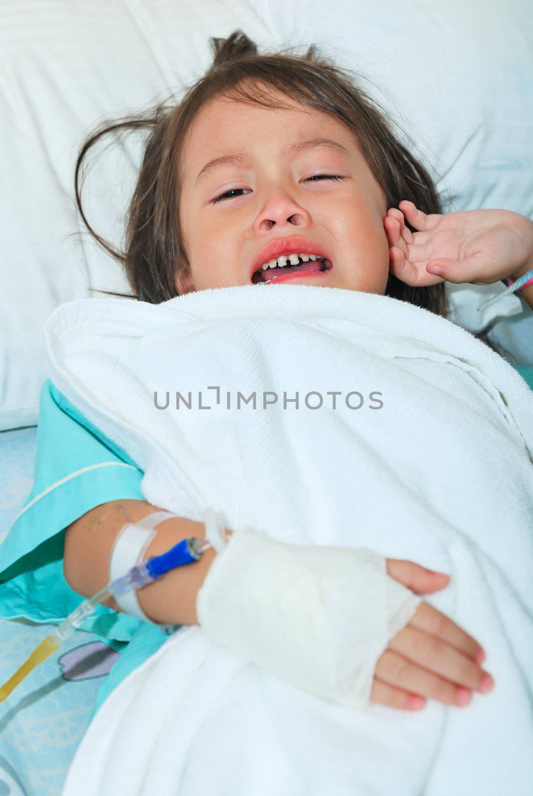 Sick little girl crying in hospital bed