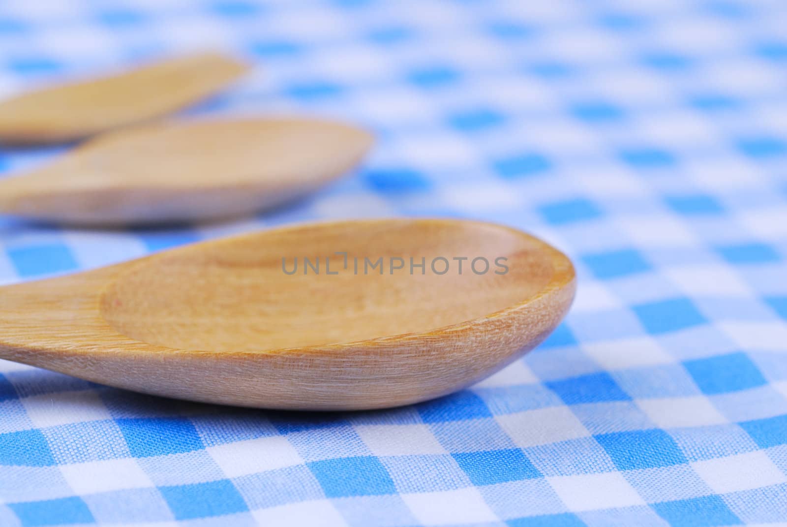 Wooden spoon,  tablecloth, fork on table background