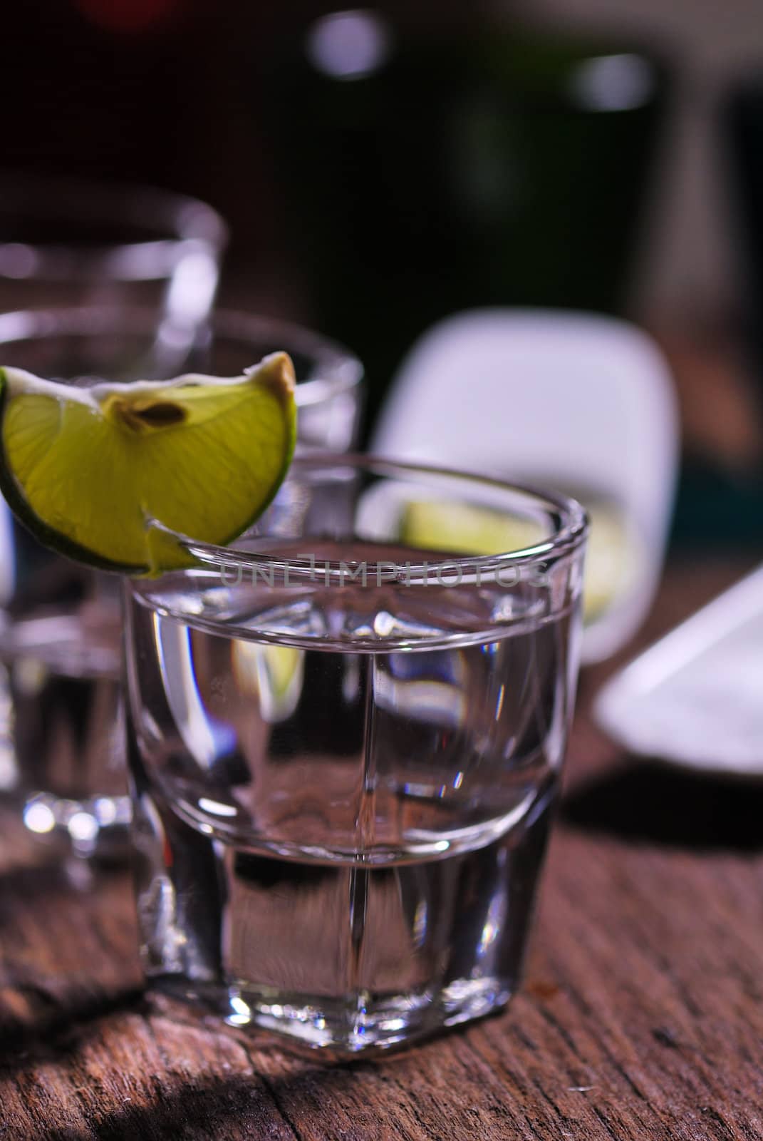 Glass of vodka shot with fresh lime on wooden table