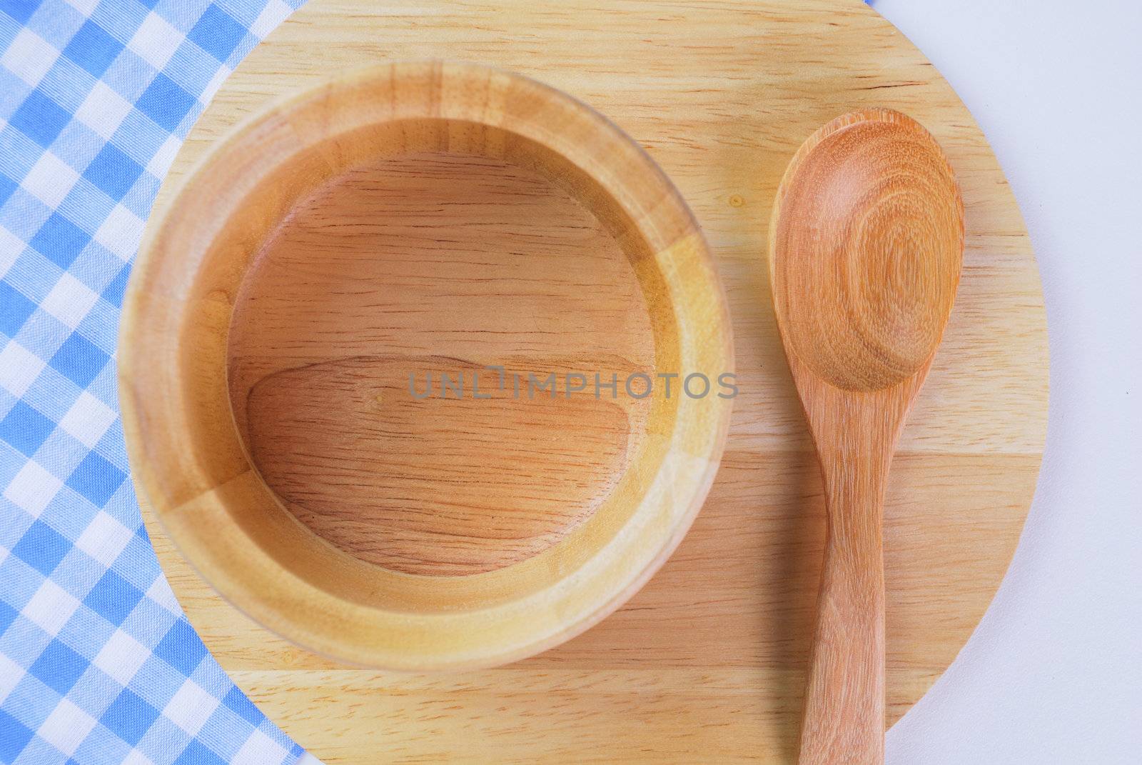 Wooden plate, tablecloth, spoon, fork on table background