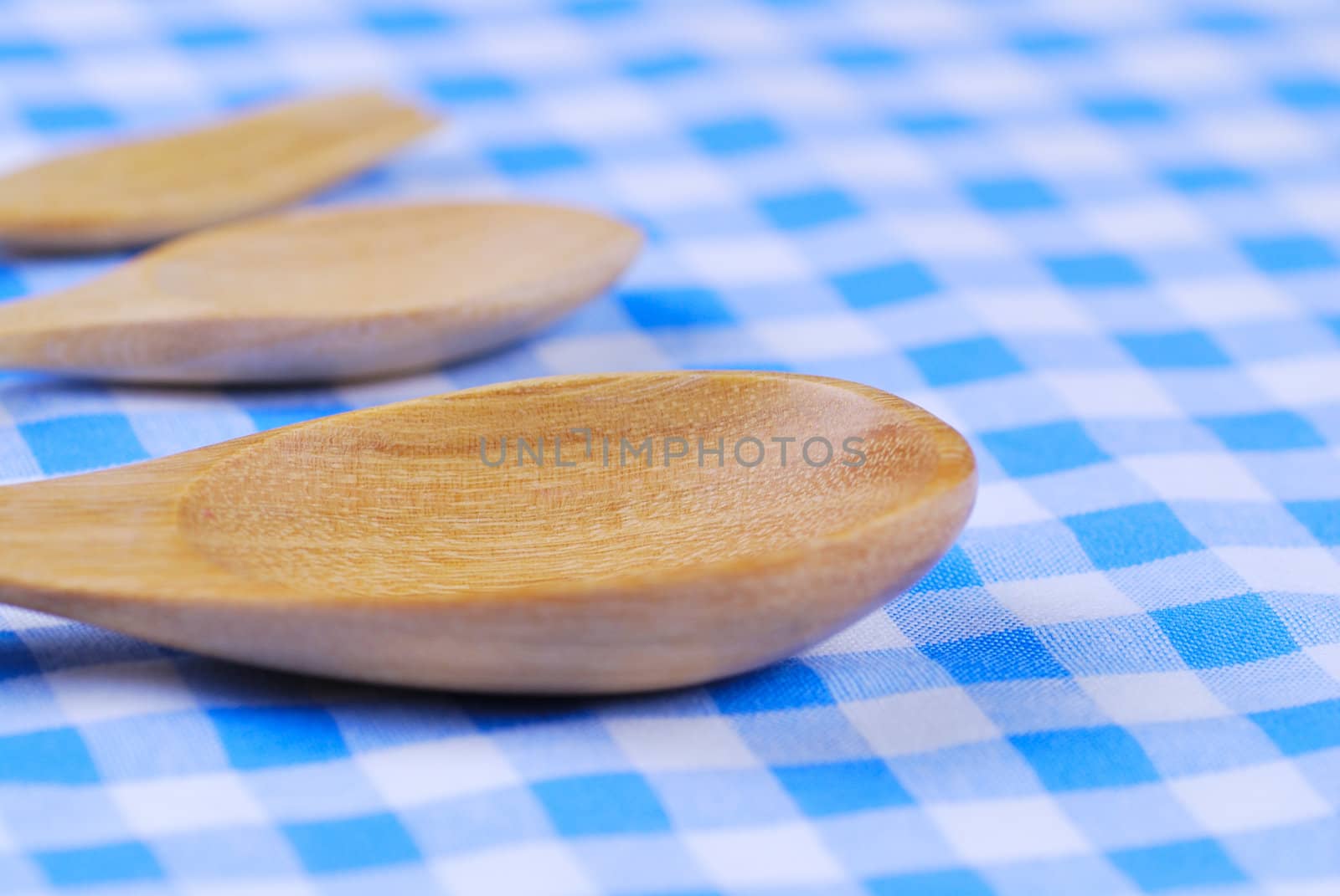 Wooden spoon,  tablecloth, fork on table background