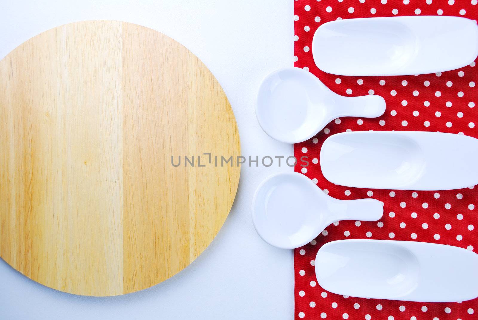 Wooden plate, tablecloth, spoon, fork on table background