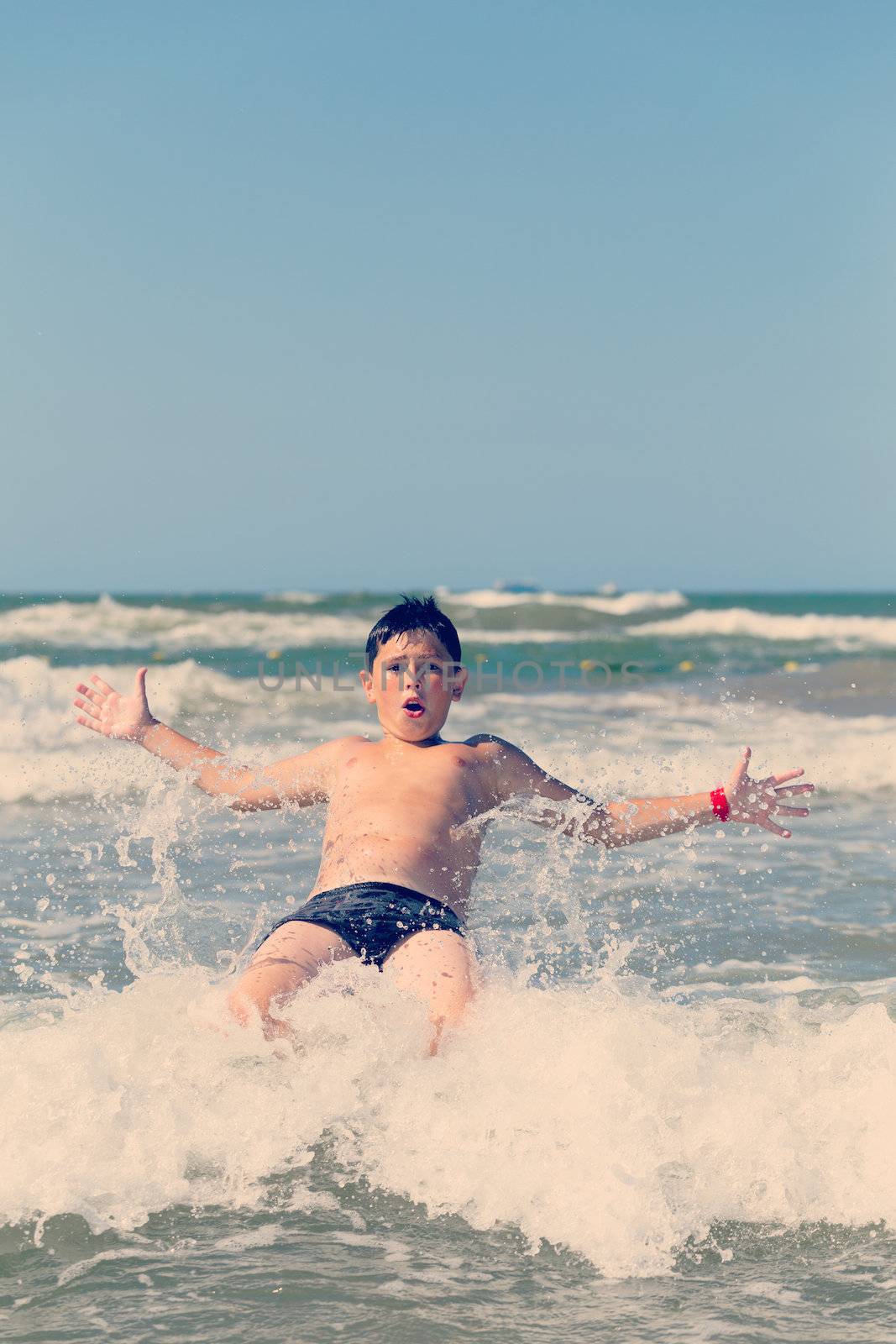 Happy boy running and jumping at shallow sea water, retro color tone