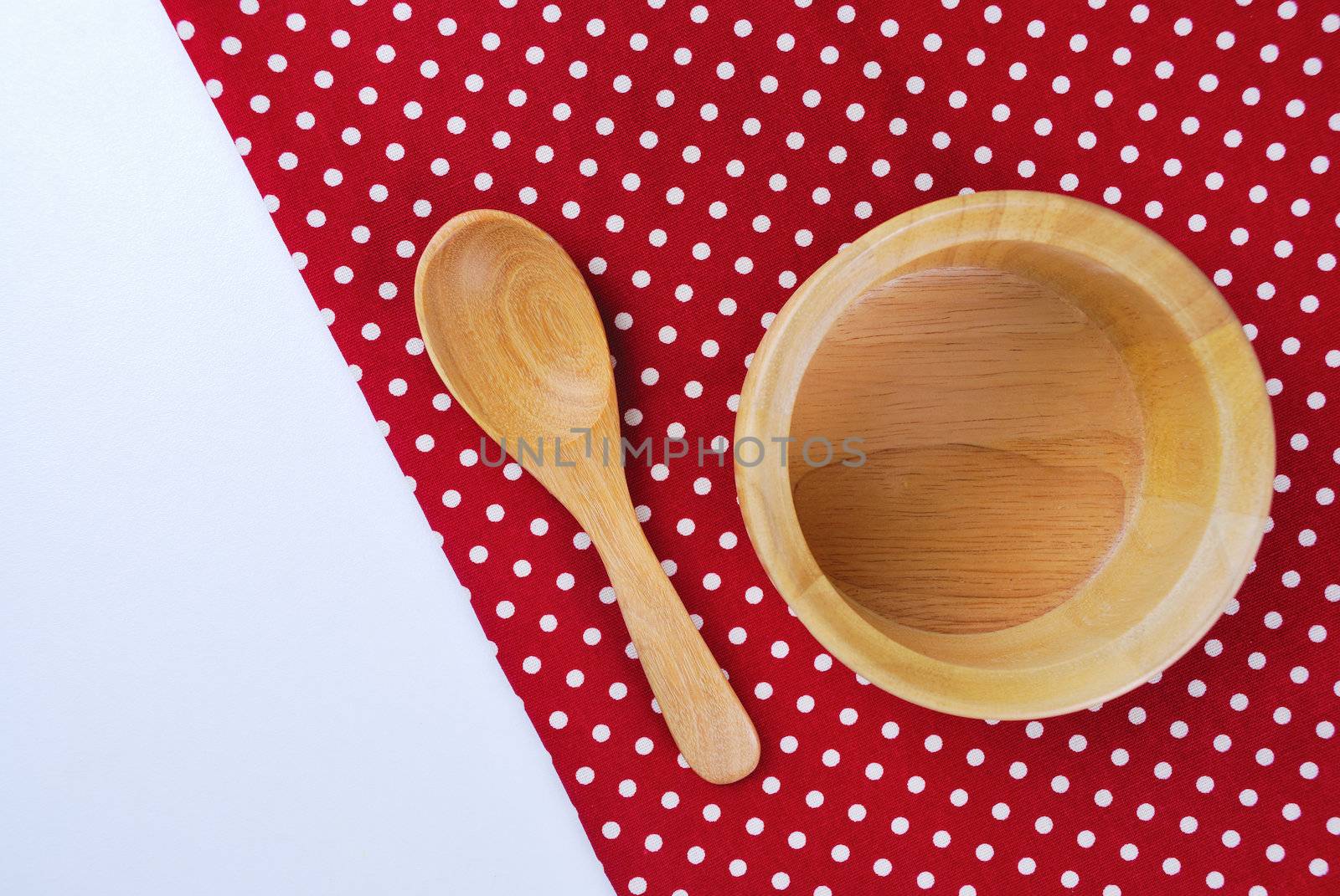 Wooden bowl, tablecloth, spoon, fork on table background