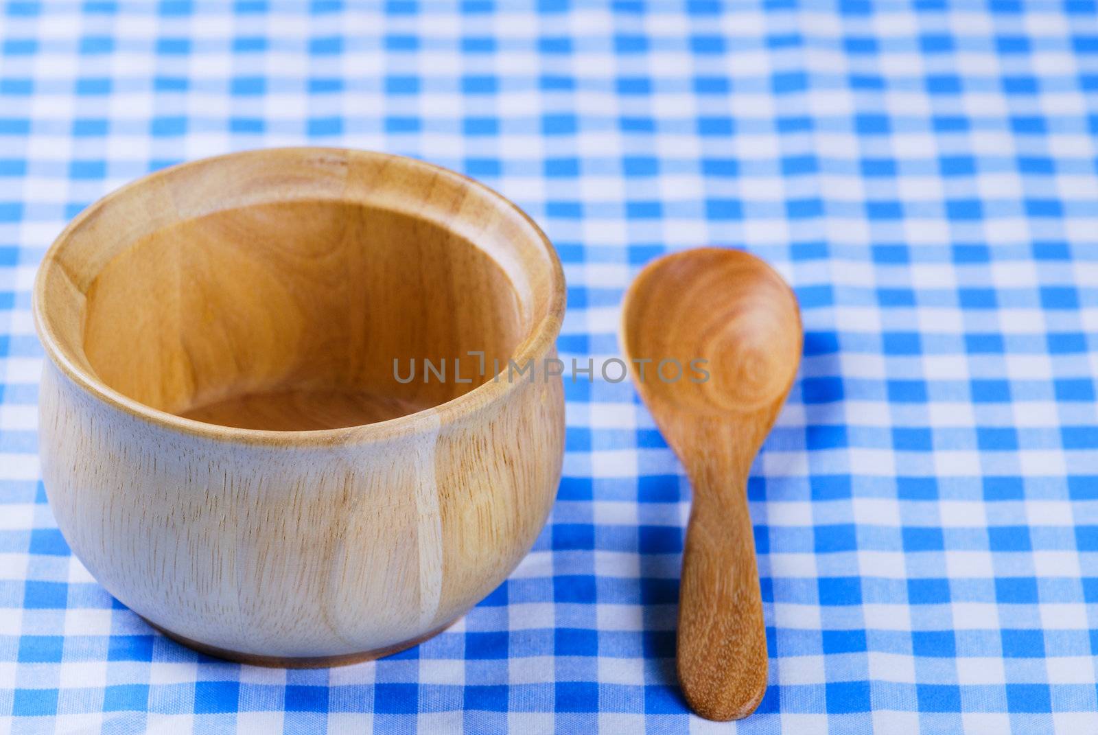 Wooden bowl, tablecloth, spoon, fork on table background